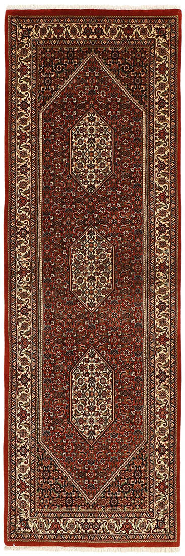 Red and cream persian wool and silk runner with traditional floral design
