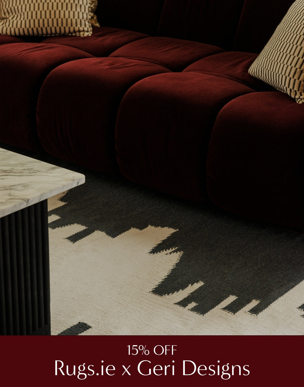 Red tufted sofa with a patterned rug and marble coffee table in a living room setting.
