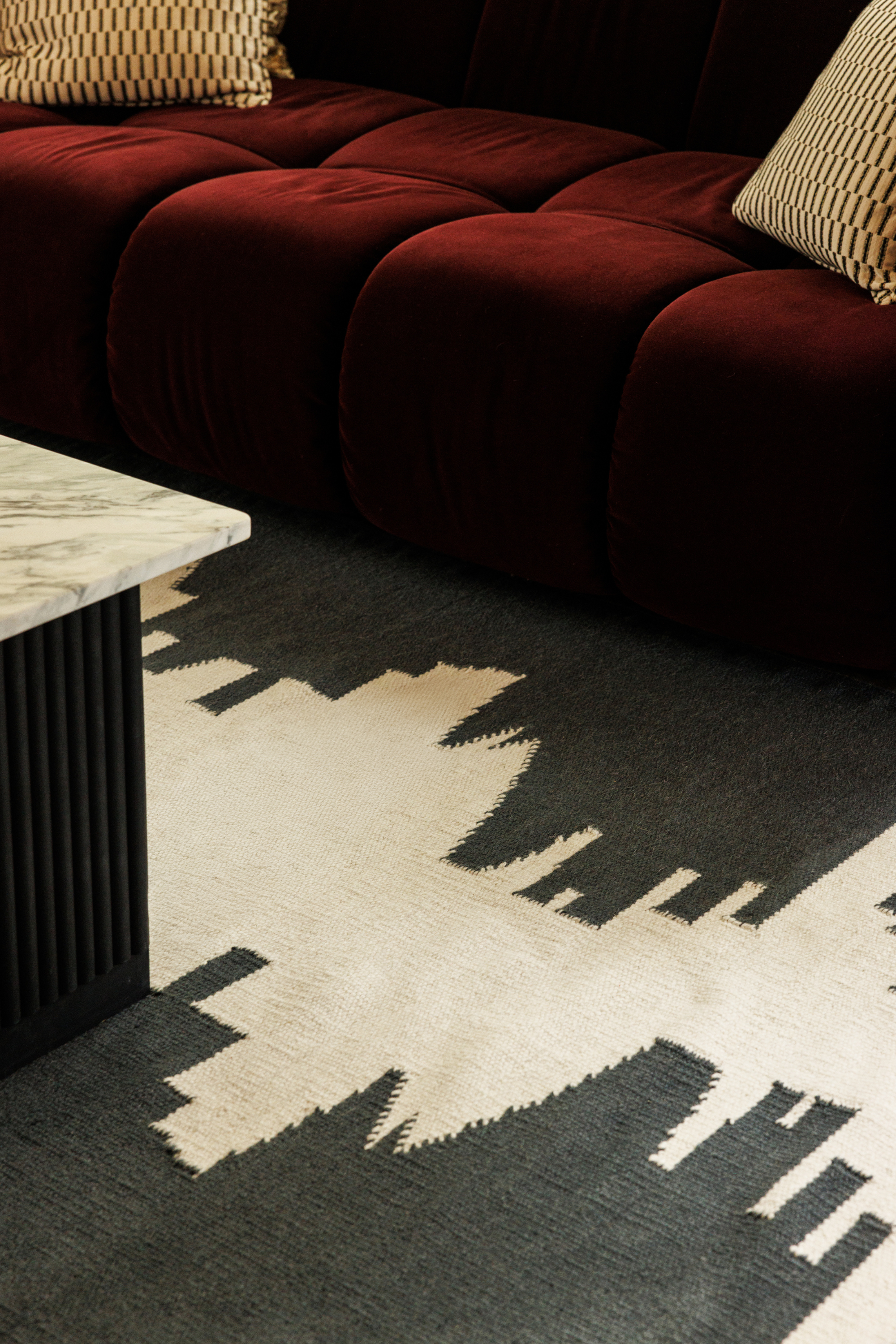 a black and white wool and cotton rug featuring a monochromatic modern abstract design placed under a couch in a living room