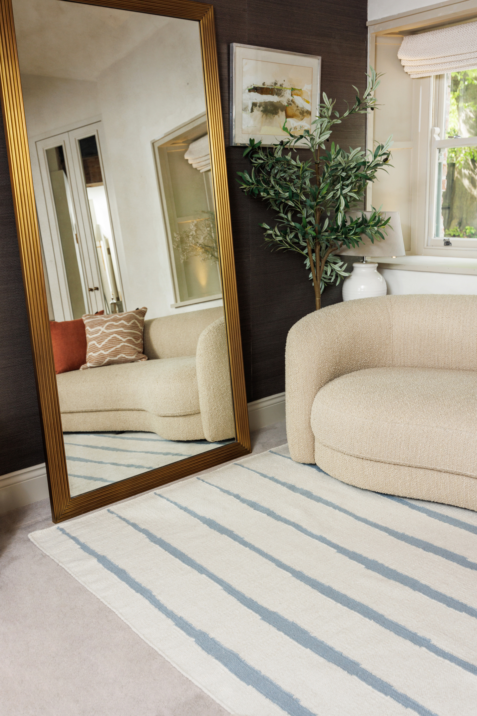 Neutral ivory wool and cotton flatweave rug featuring blue ripple linear lines placed in a living room