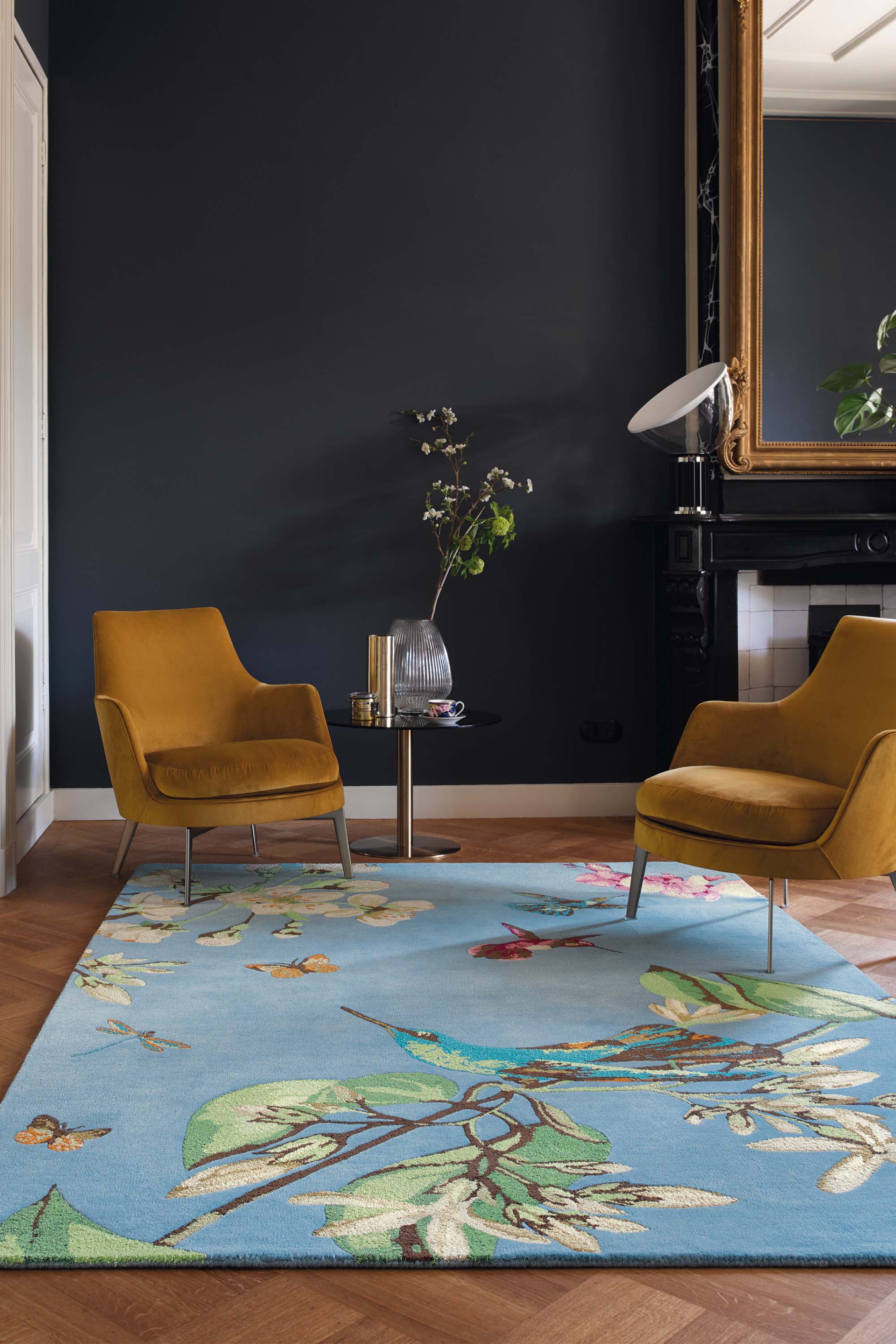 Rectangular blue rug decorated with flowers, leaves and hummingbirds