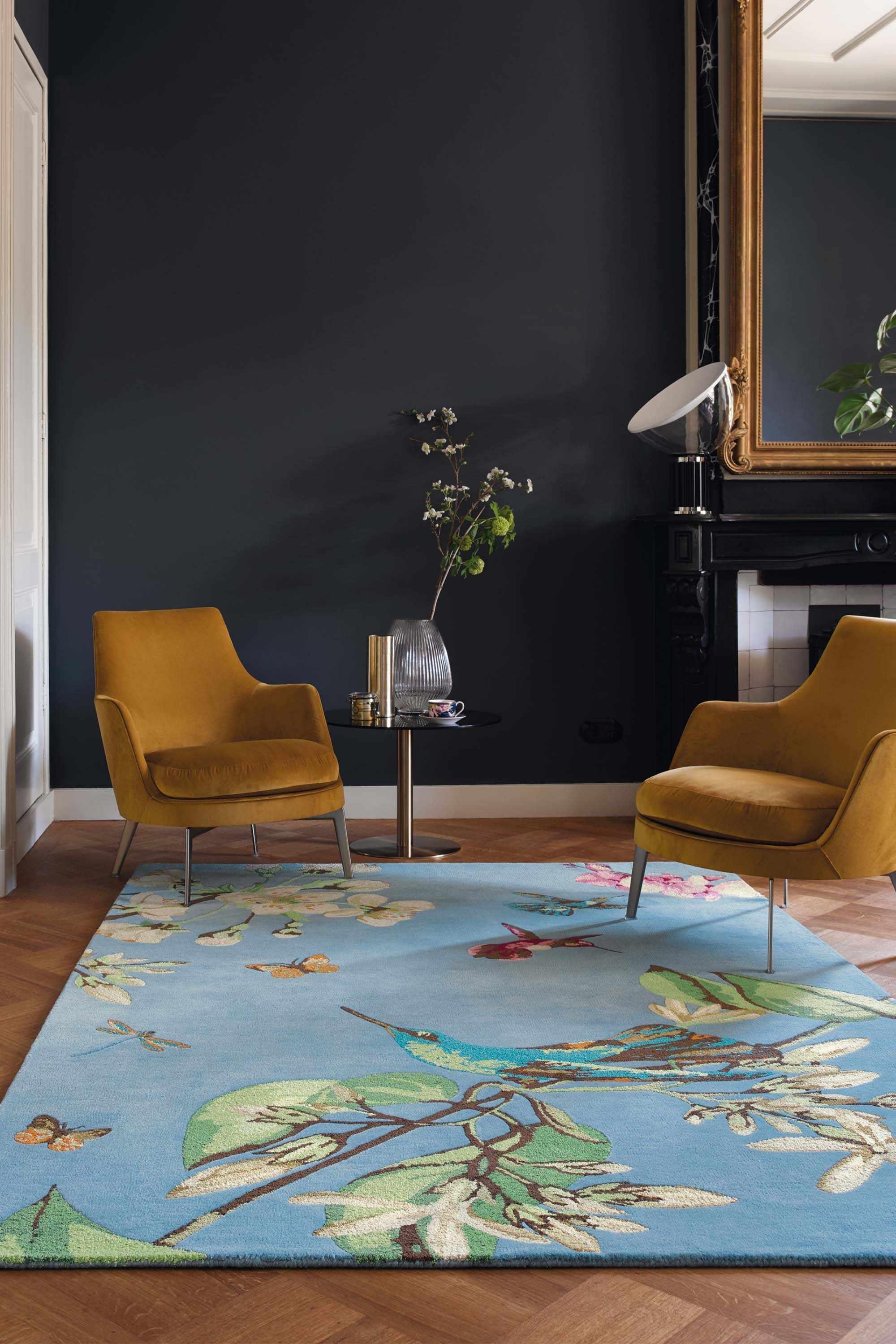 Rectangular blue rug decorated with flowers, leaves and hummingbirds
