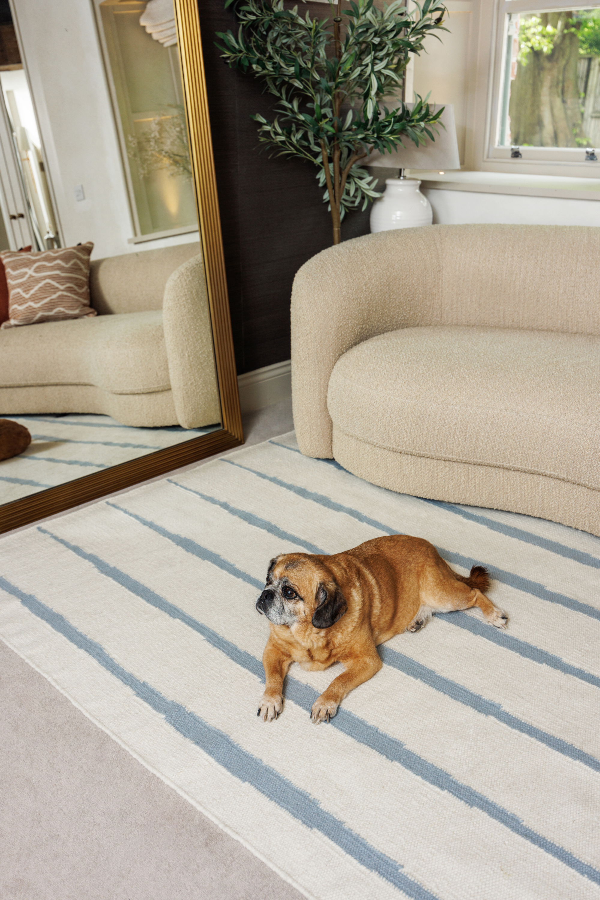 Neutral ivory wool and cotton flatweave rug featuring blue ripple linear lines placed in a living room