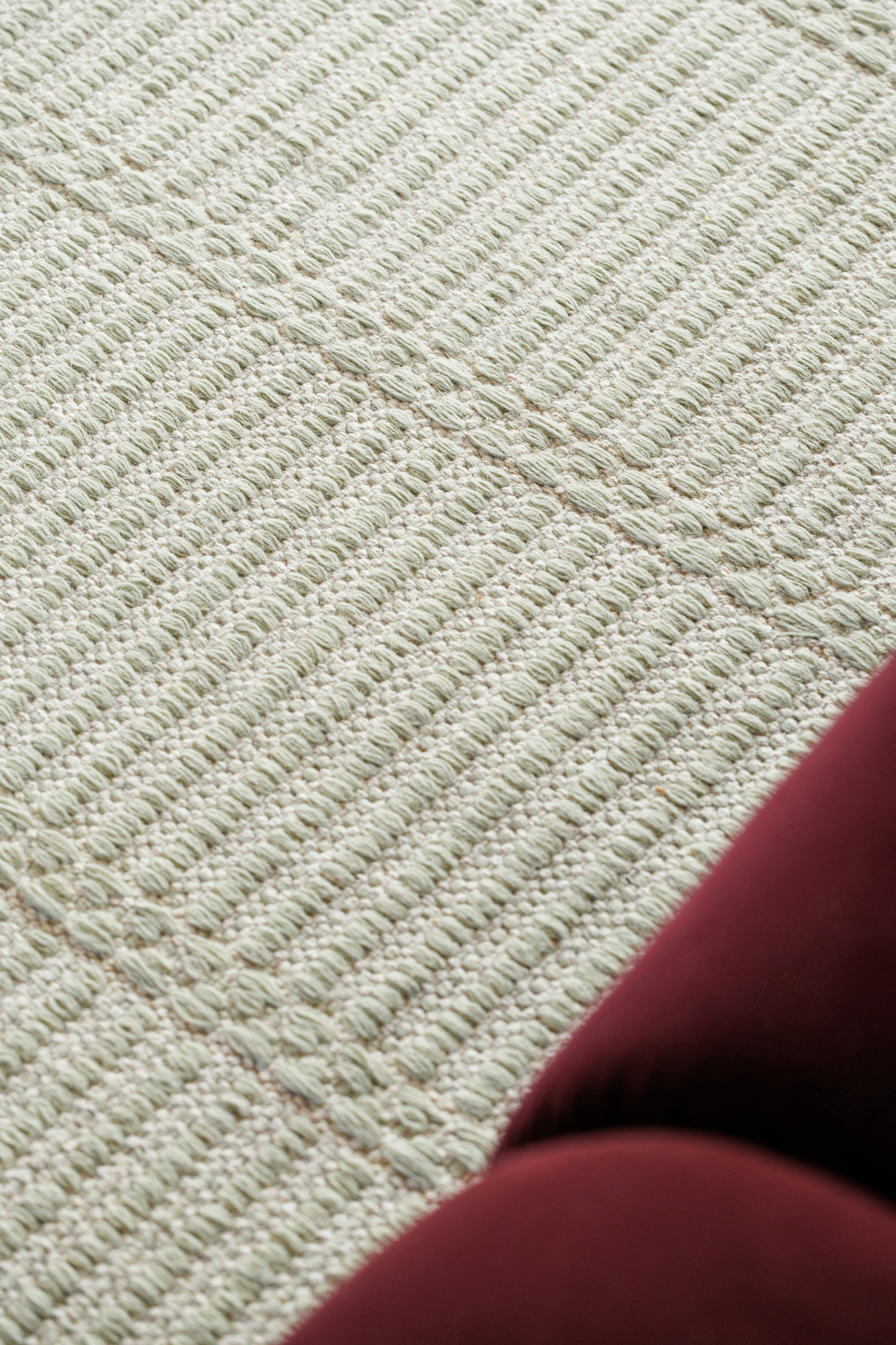 wool and cotton rug in soft olive hues featuring a design inspired by ancient irish script