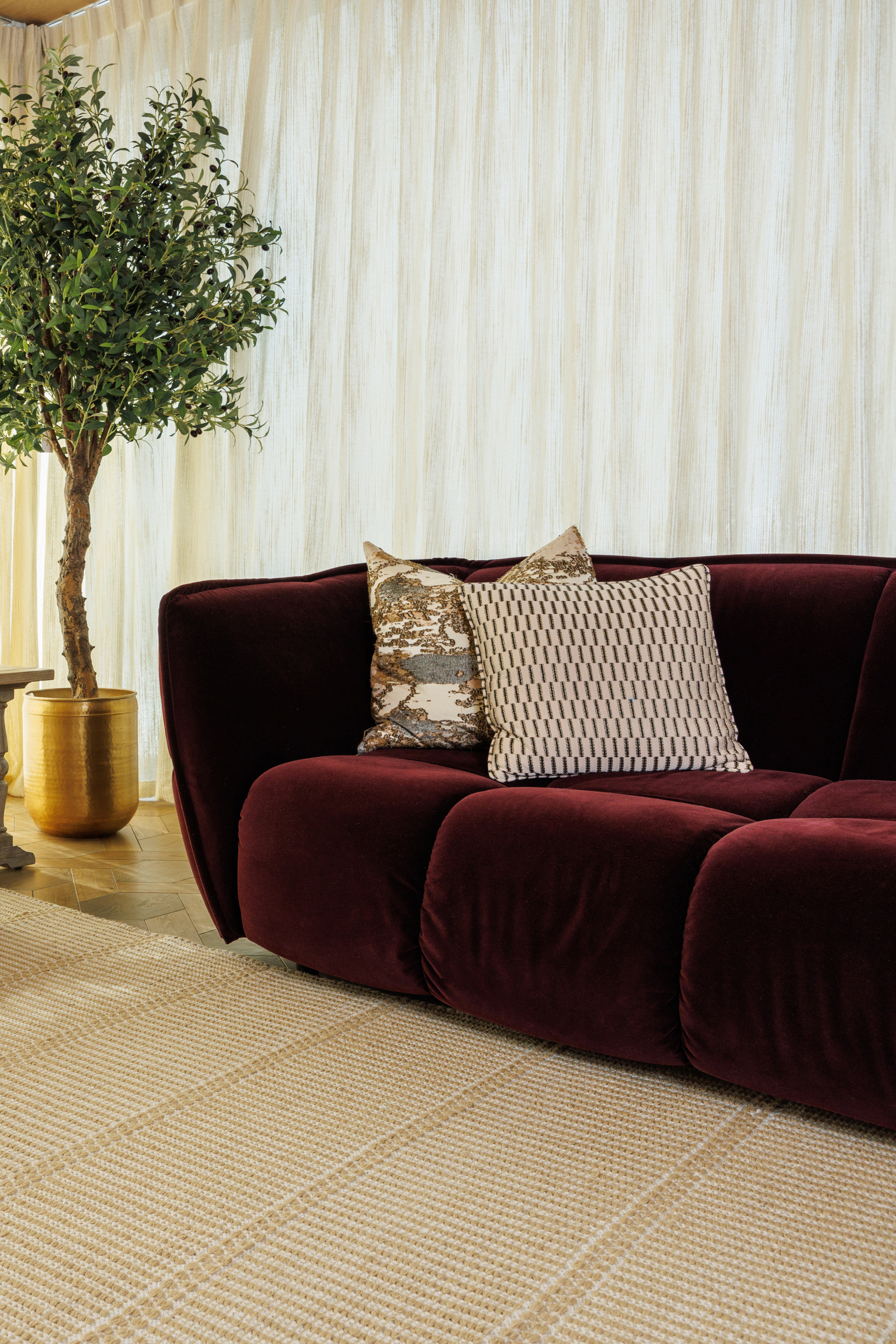 wool and cotton rug in a golden straw tone featuring a design inspired by ancient irish script placed under a couch