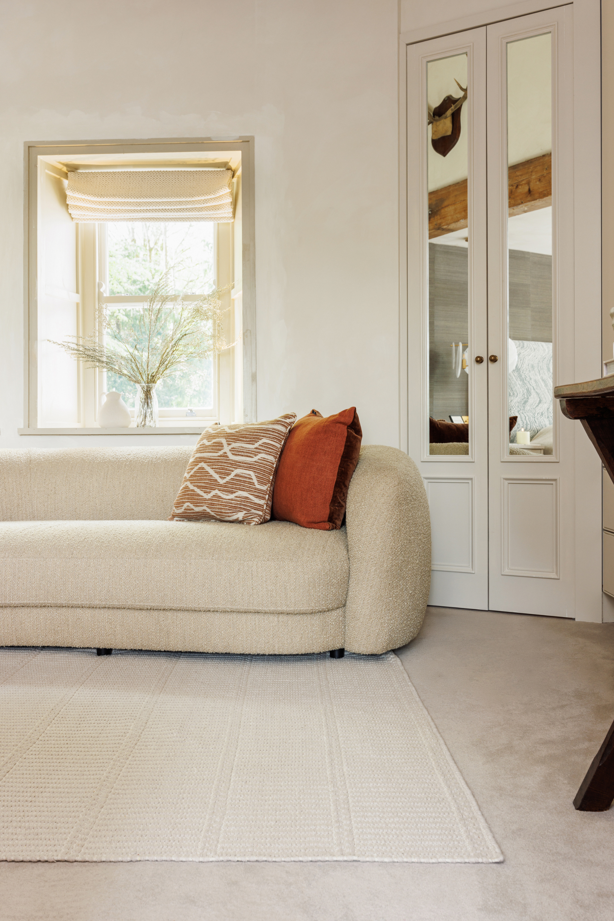 beige wool and cotton rug featuring a design inspired by ancient irish script placed under a couch in a living room