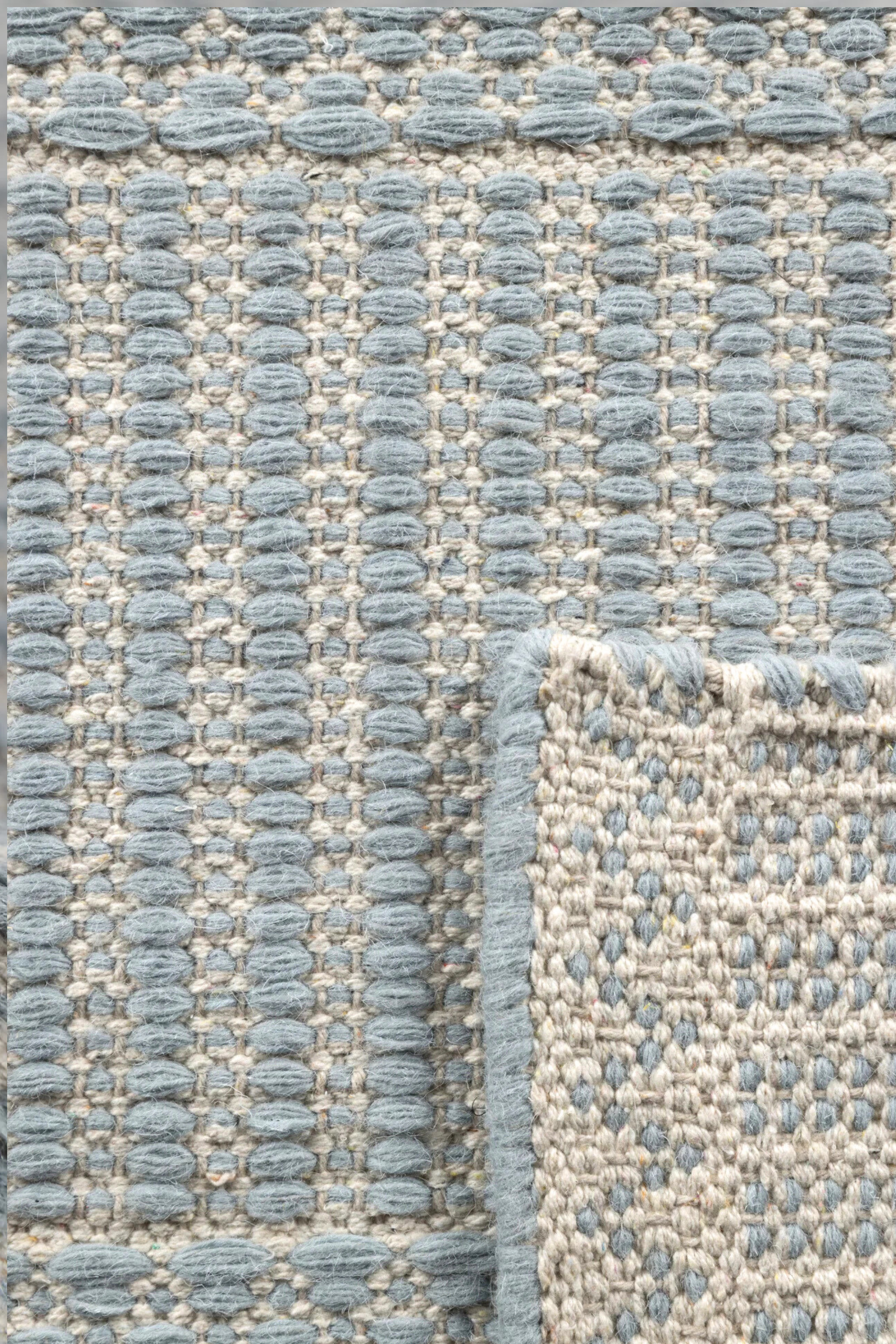 a close up of the pile of a blue wool and cotton rug featuring a design inspired by ancient irish script