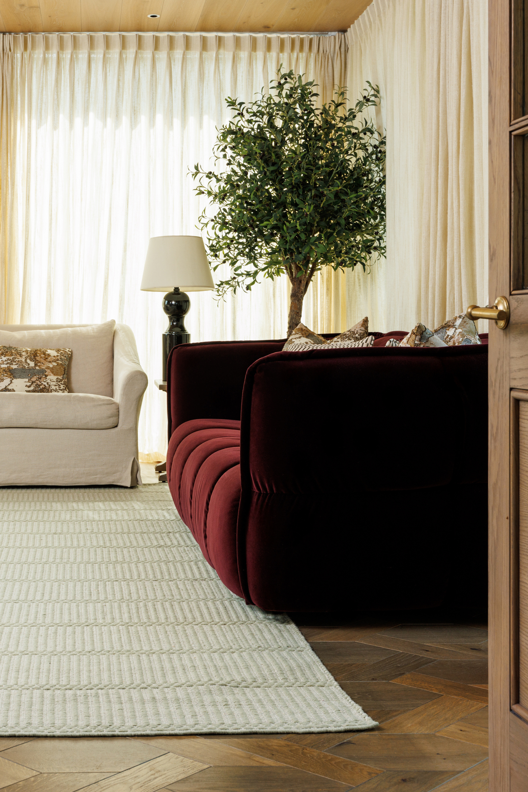 wool and cotton rug in soft olive hues featuring a design inspired by ancient irish script palced under a couch in a living room