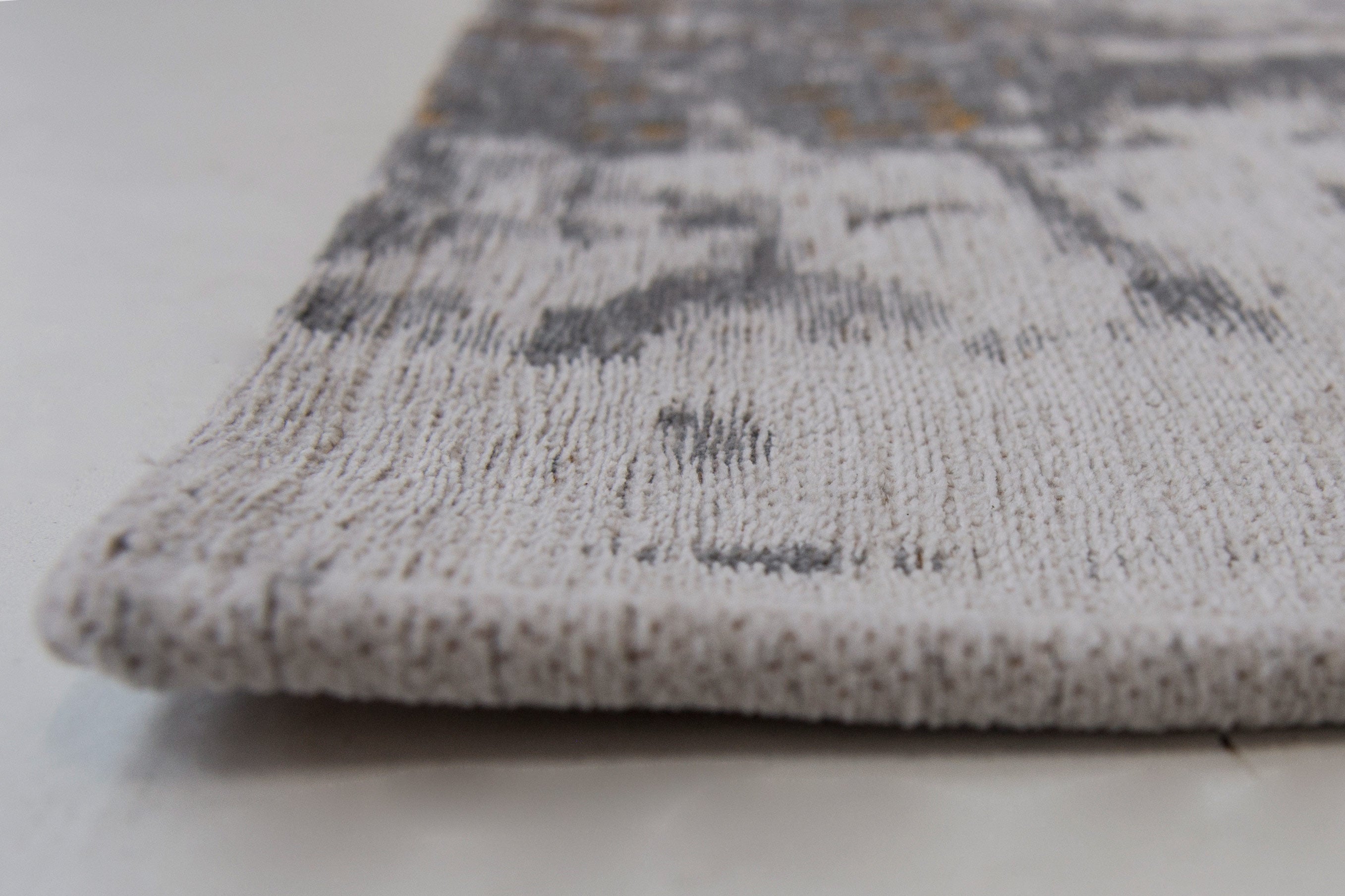 White flatweave rug with grey and yellow abstract pattern