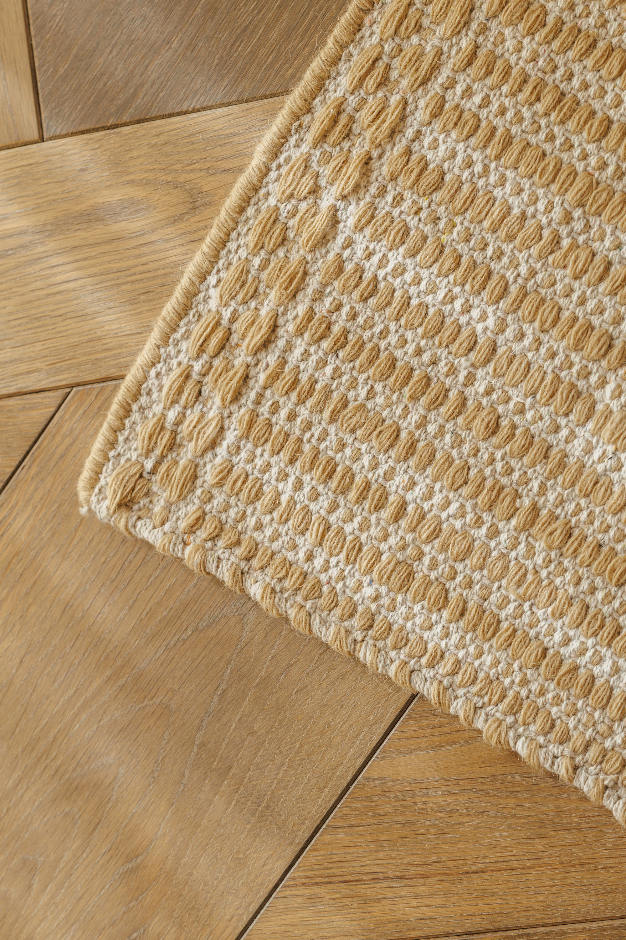 wool and cotton rug in a golden straw tone featuring a design inspired by ancient irish script