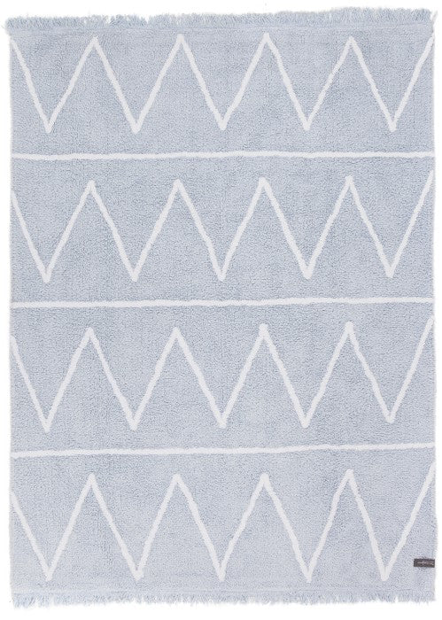 Rectangular blue rug decorated with white zig-zag design and fringed border