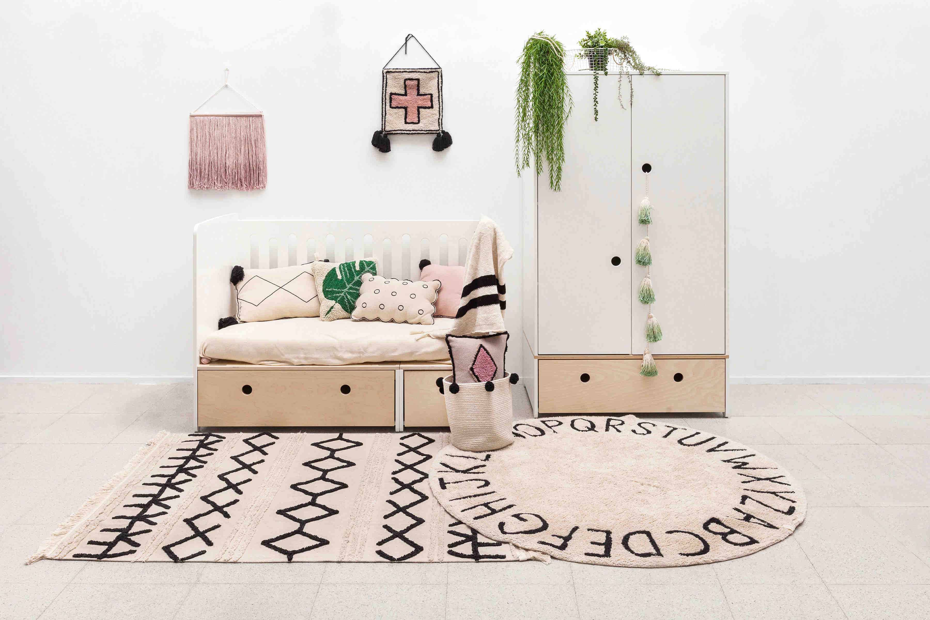 Circular white cotton rug decorated with a black alphabet border