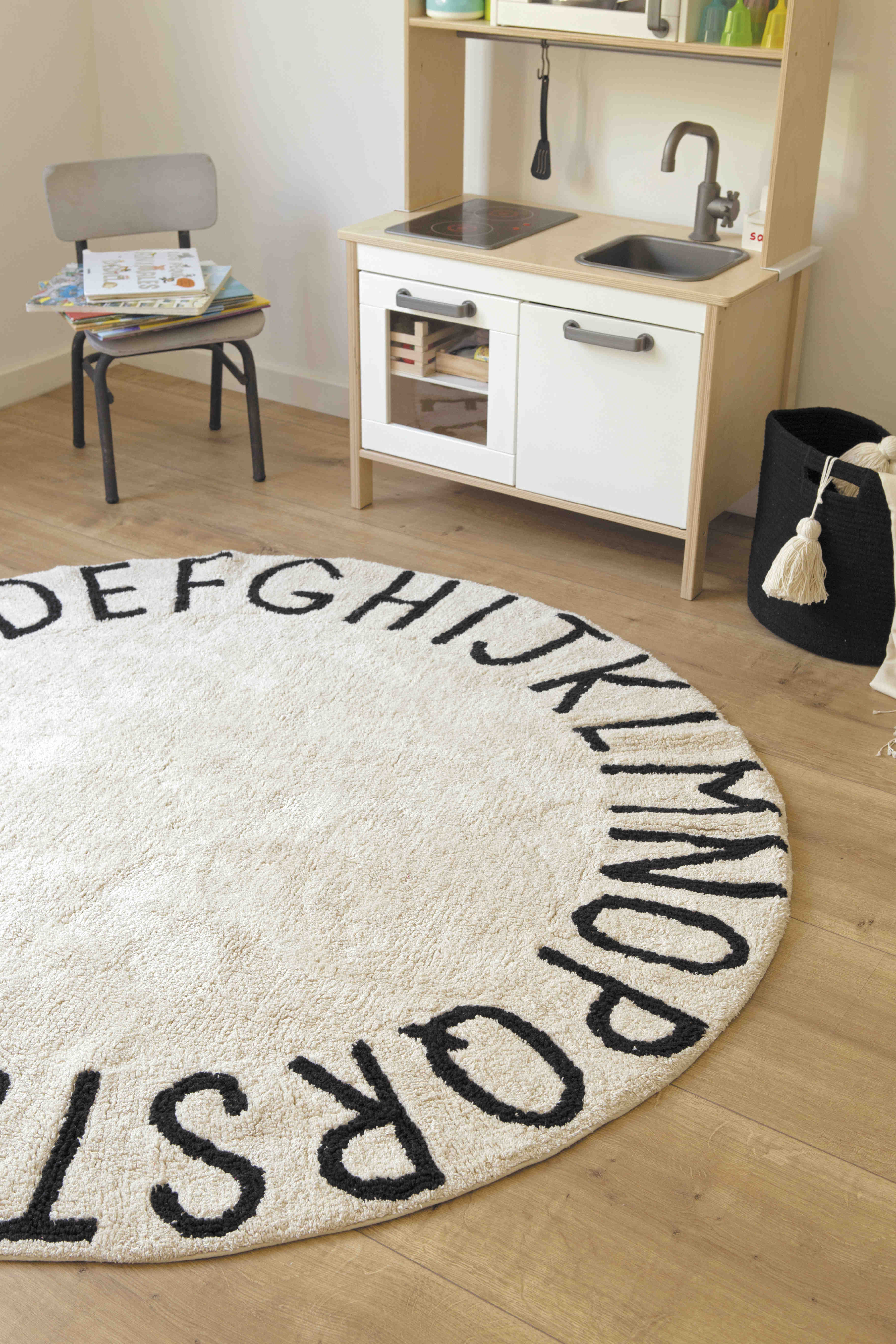 Circular white cotton rug decorated with a black alphabet border