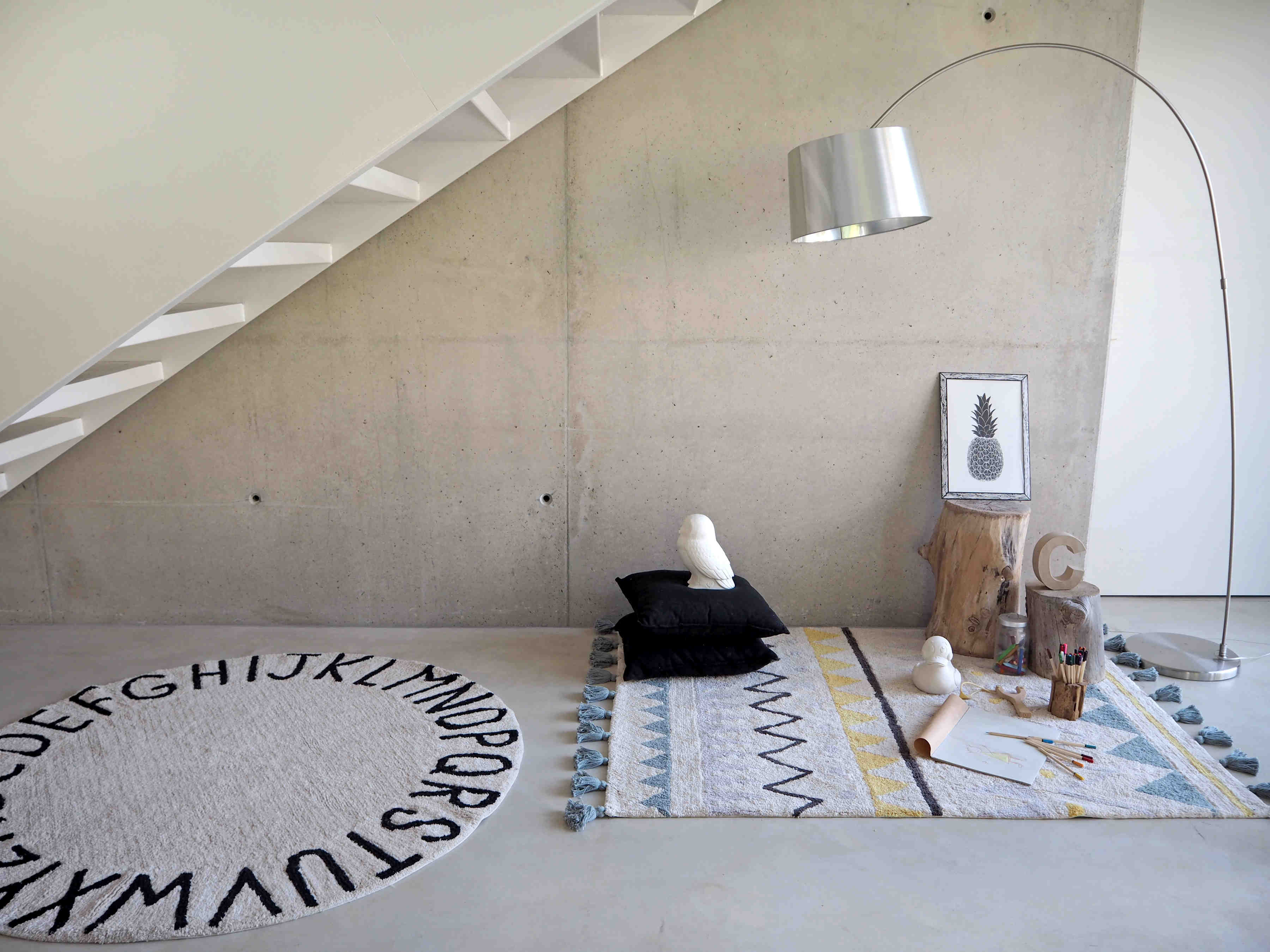 Circular white cotton rug decorated with a black alphabet border