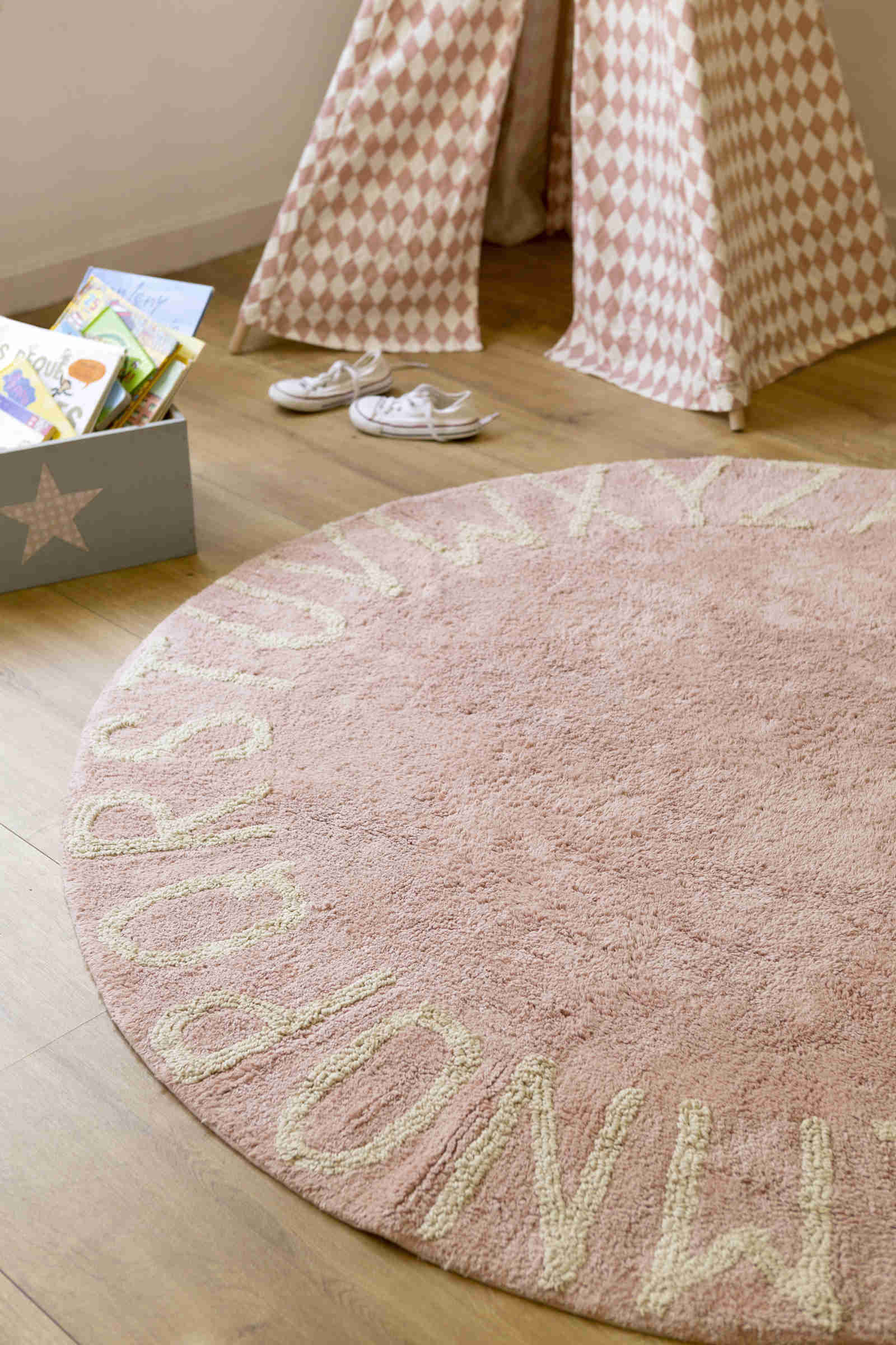 Circular pink cotton rug decorated with a natural beige alphabet border