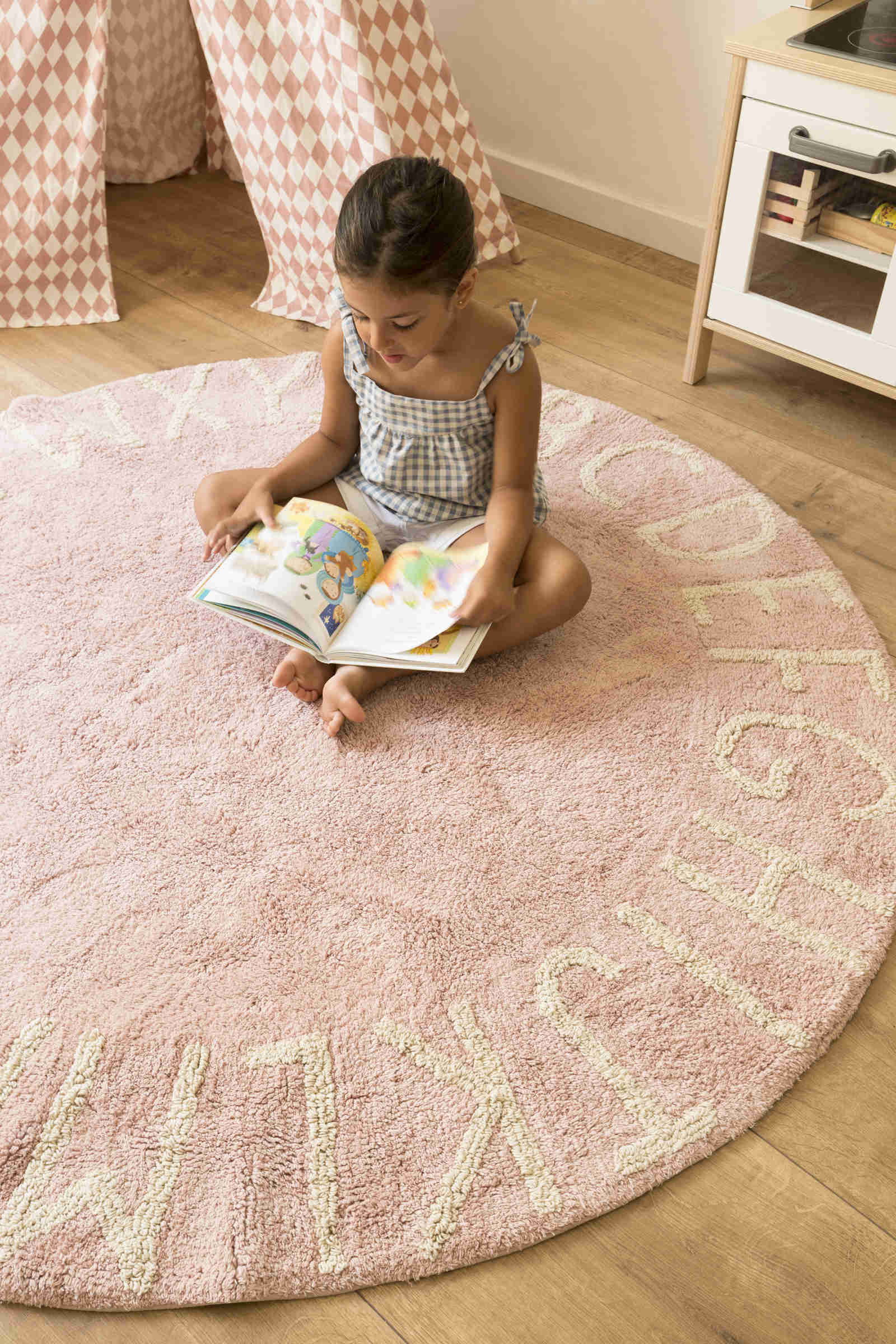 Circular pink cotton rug decorated with a natural beige alphabet border