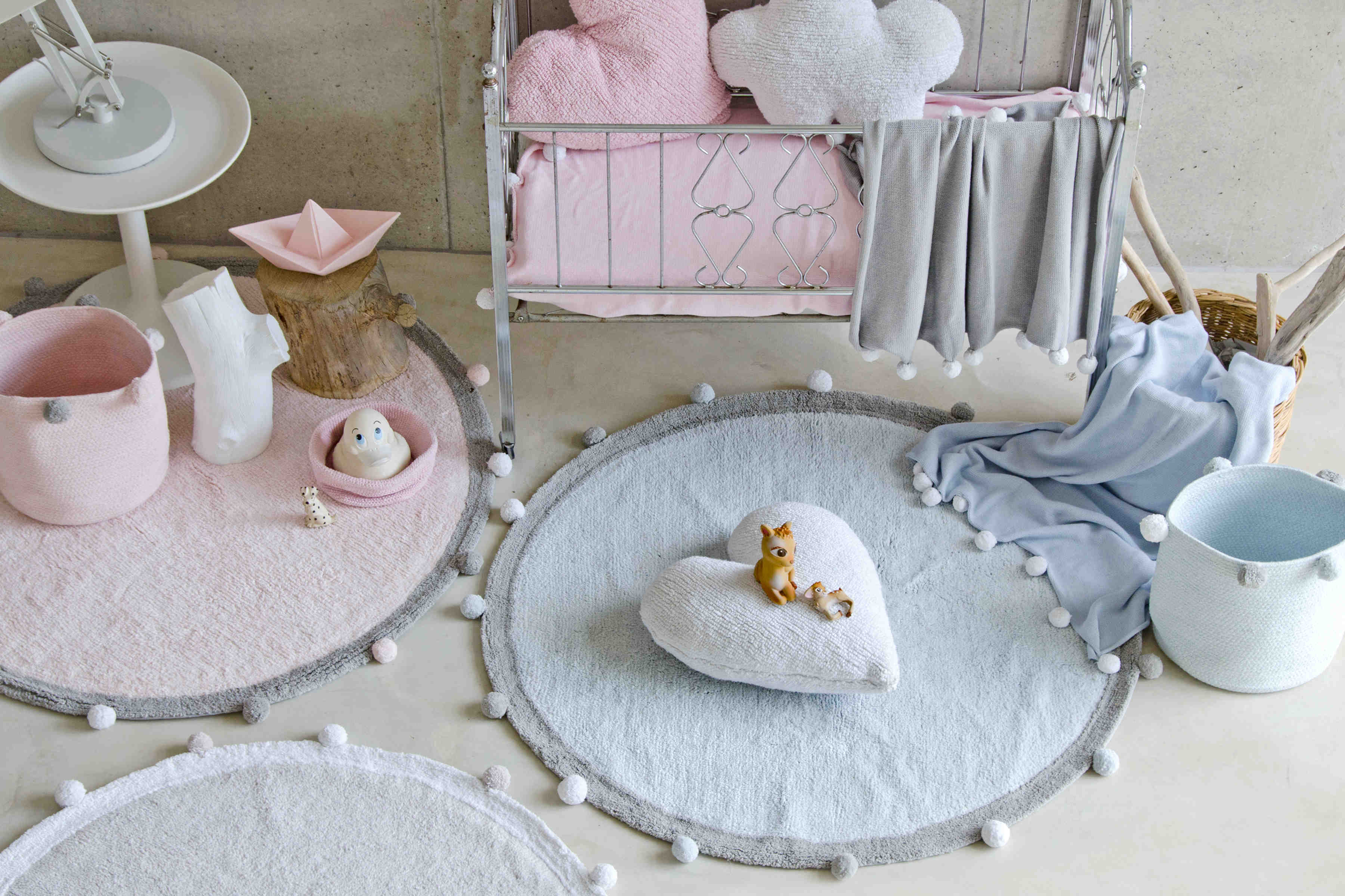 Circular pastel pink cotton rug decorated with a grey and white pom pom border