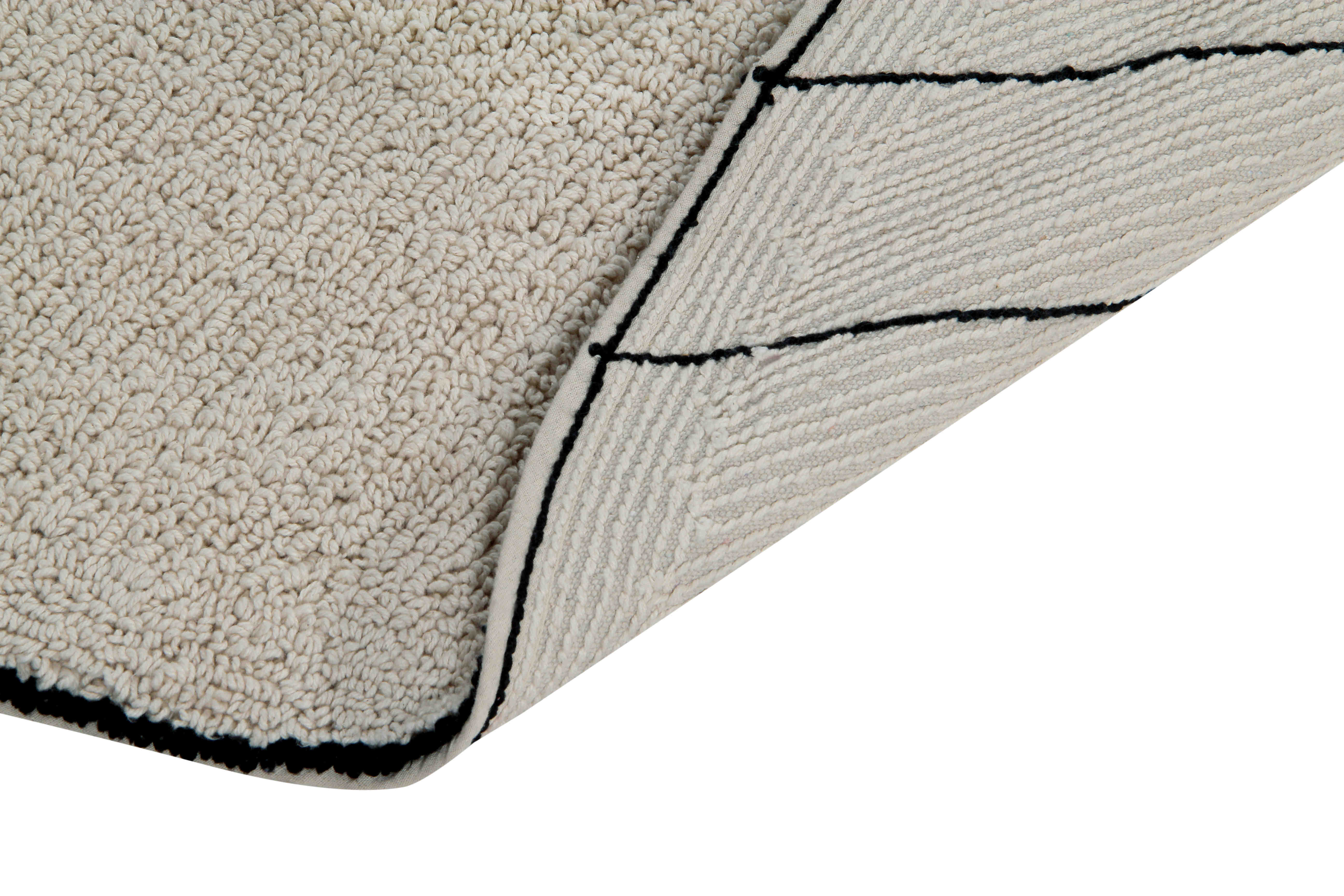 A circular shaped beige cotton rug decorated with geometric black lines