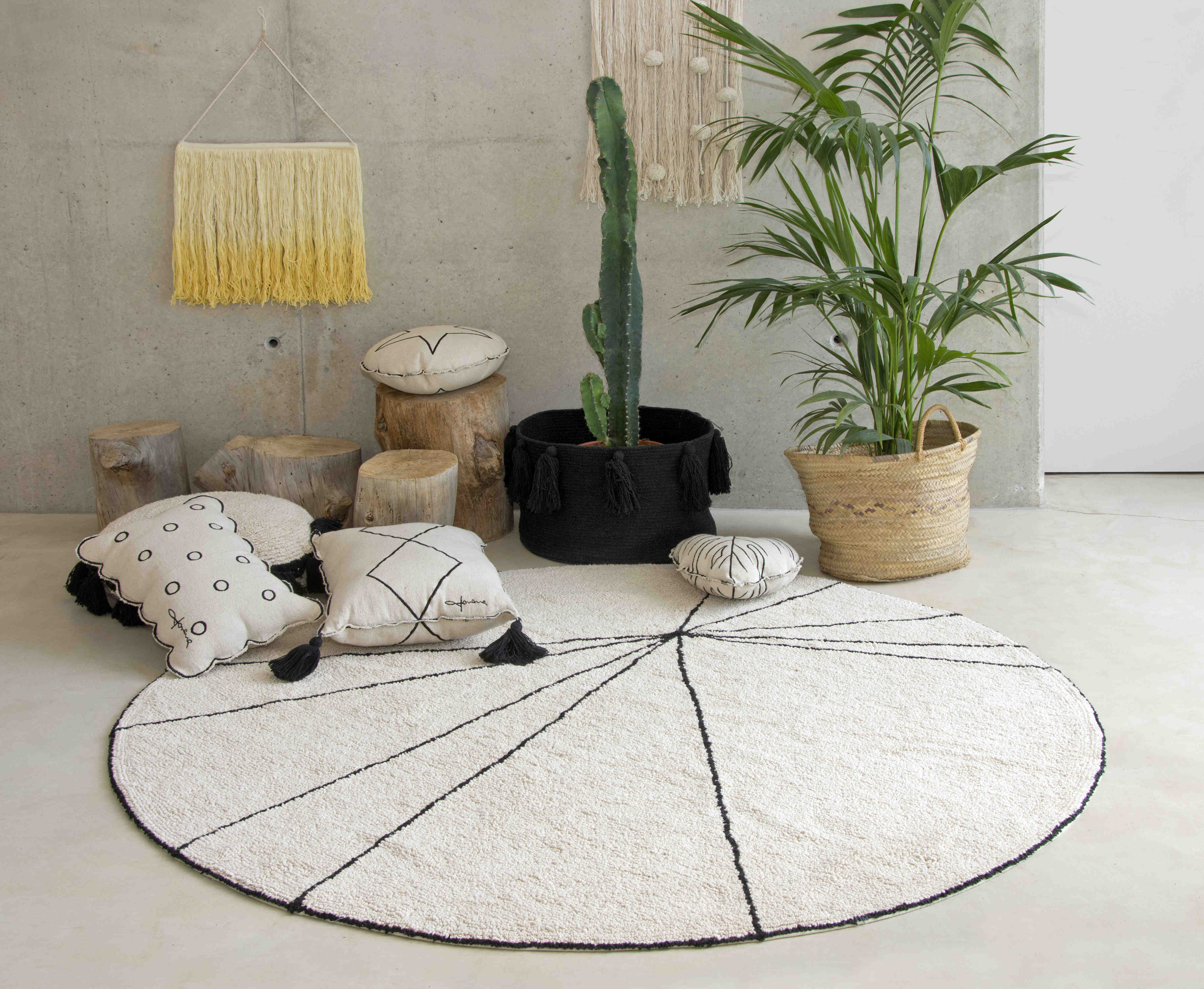 A circular shaped beige cotton rug decorated with geometric black lines