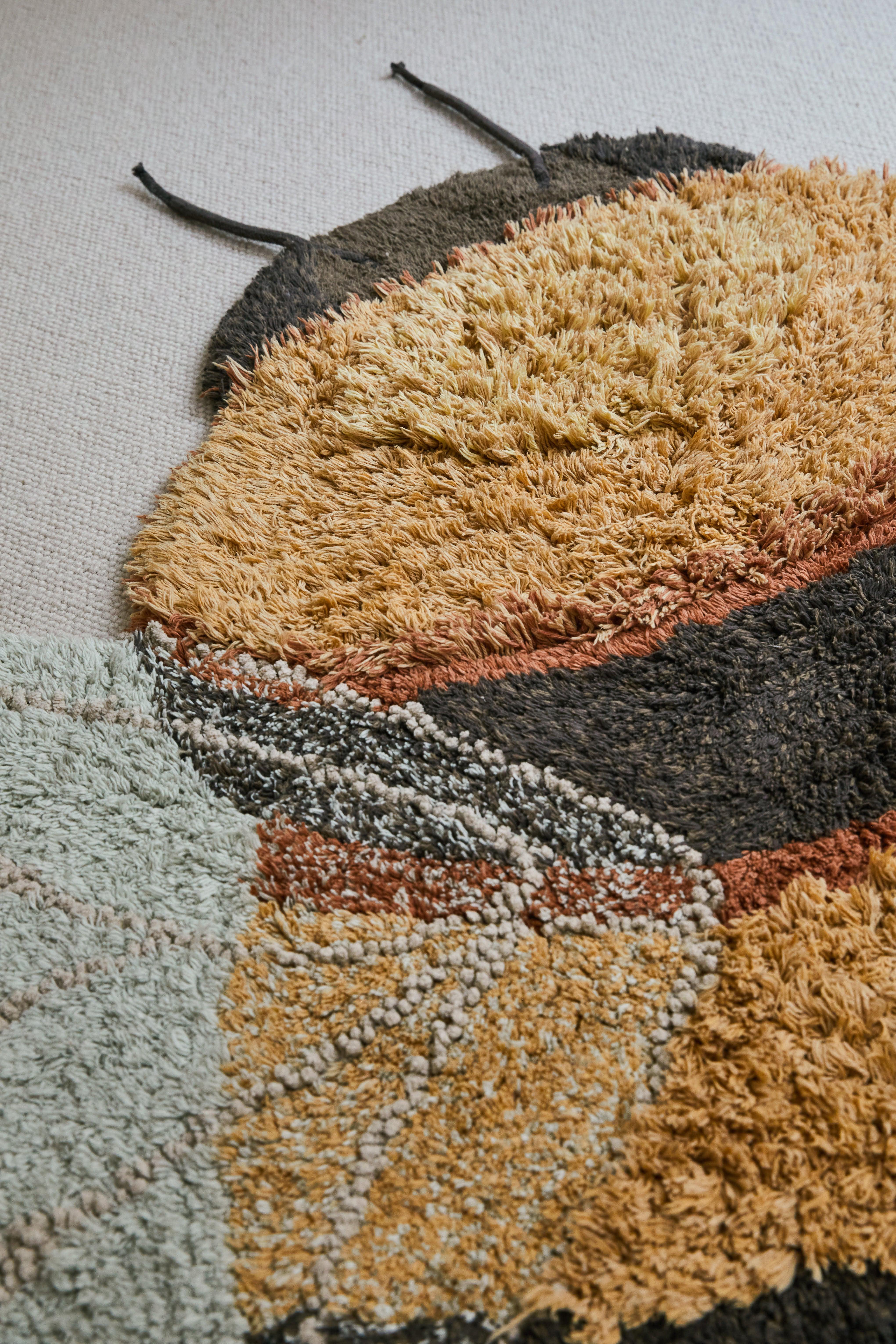 Bee-shaped rug with shades of gold, orange, brown, cream, and beige