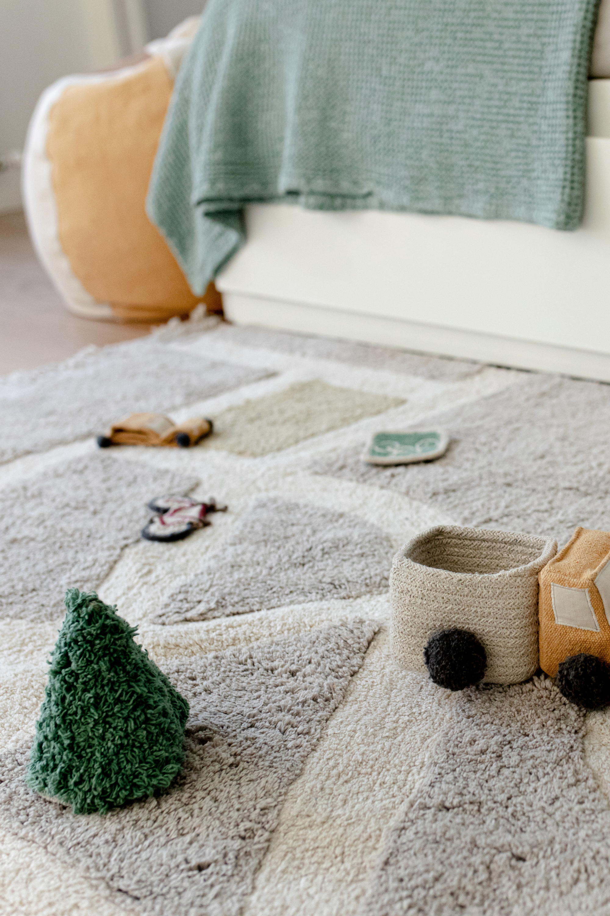 Grey, cream, blue, and green rug with city plan pattern and added city toys