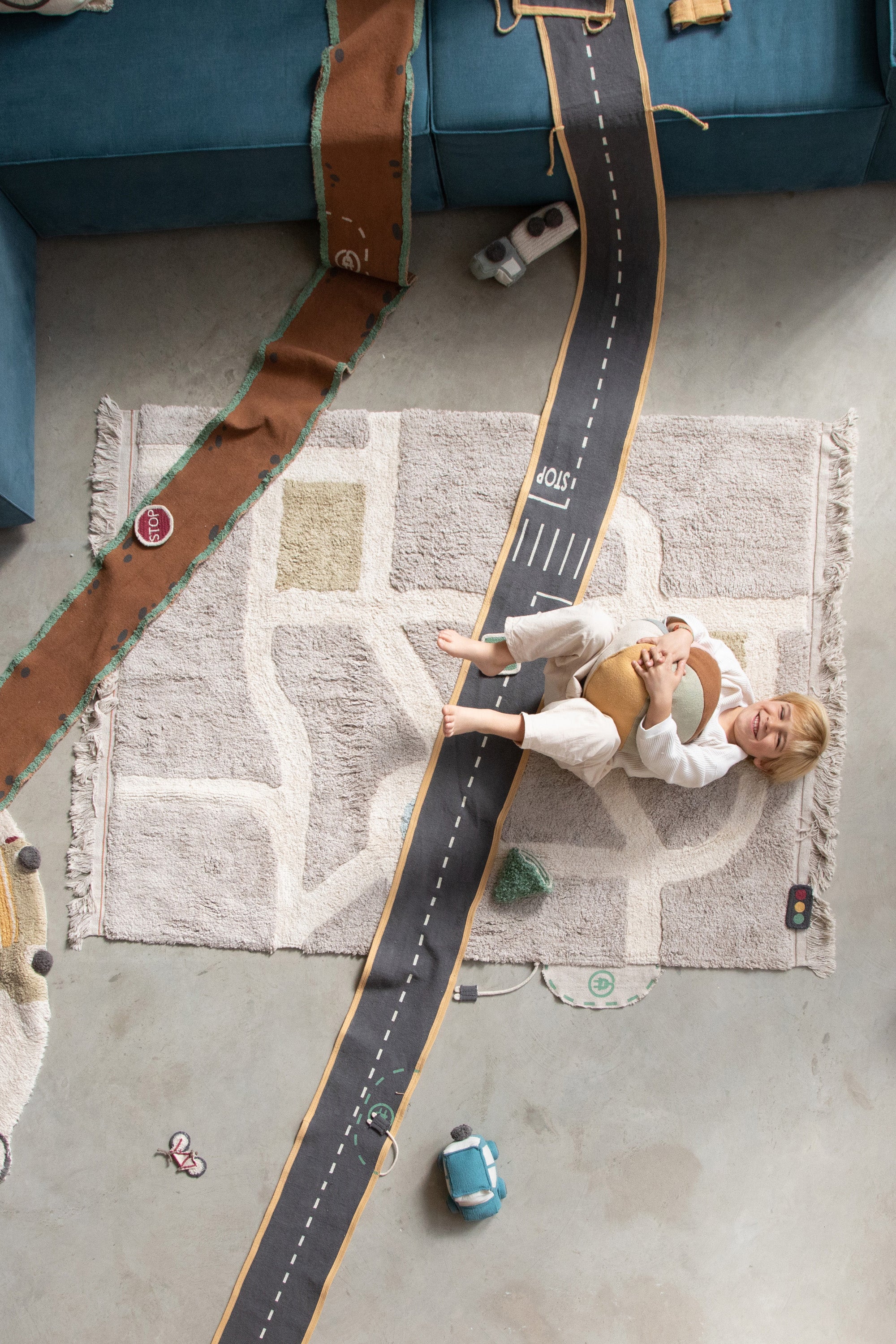 Grey, cream, blue, and green rug with city plan pattern and added city toys