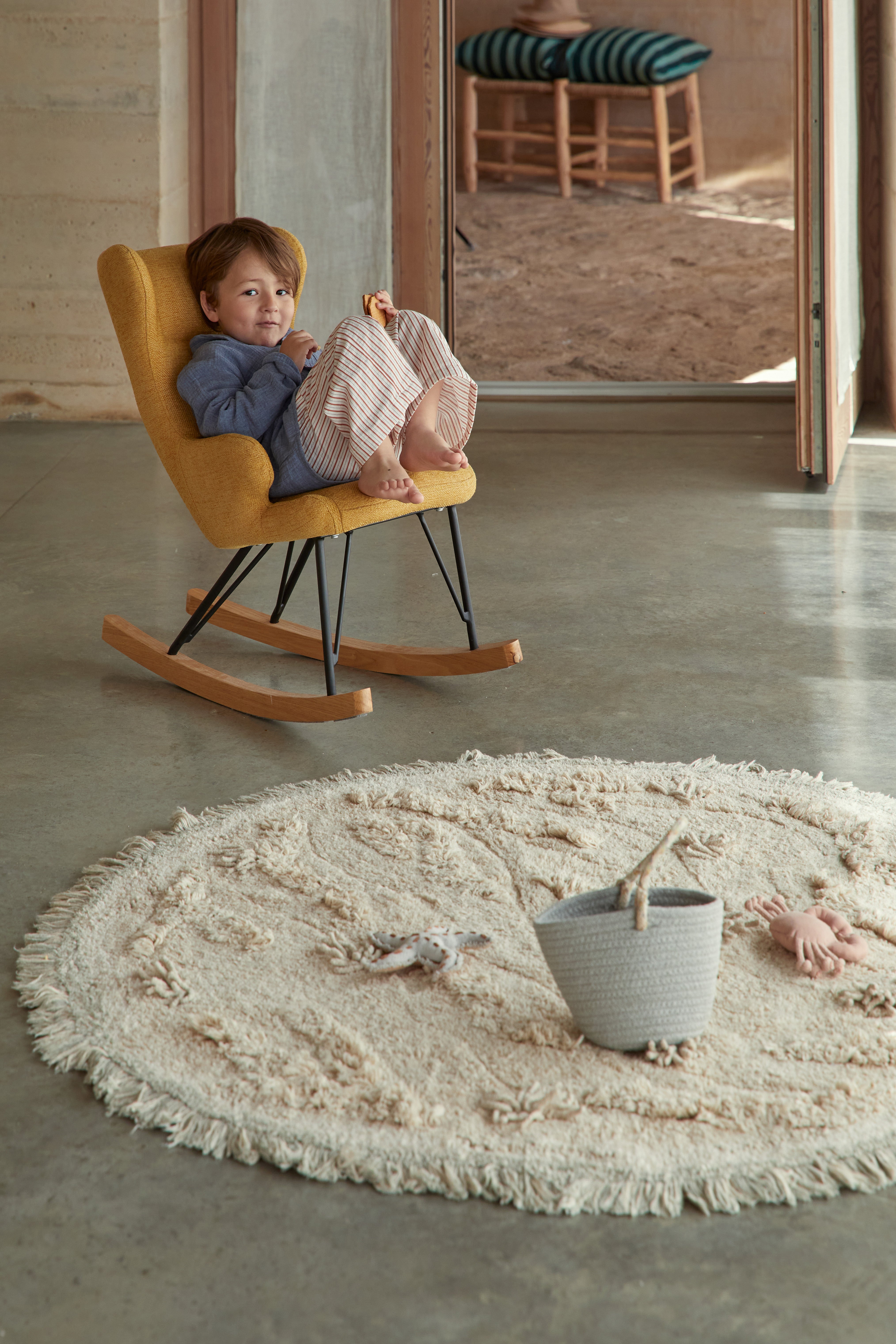 Beige island inspired rug with green fringing and added beach toys