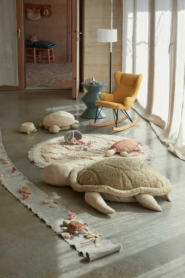 Beige island inspired rug with green fringing and added beach toys