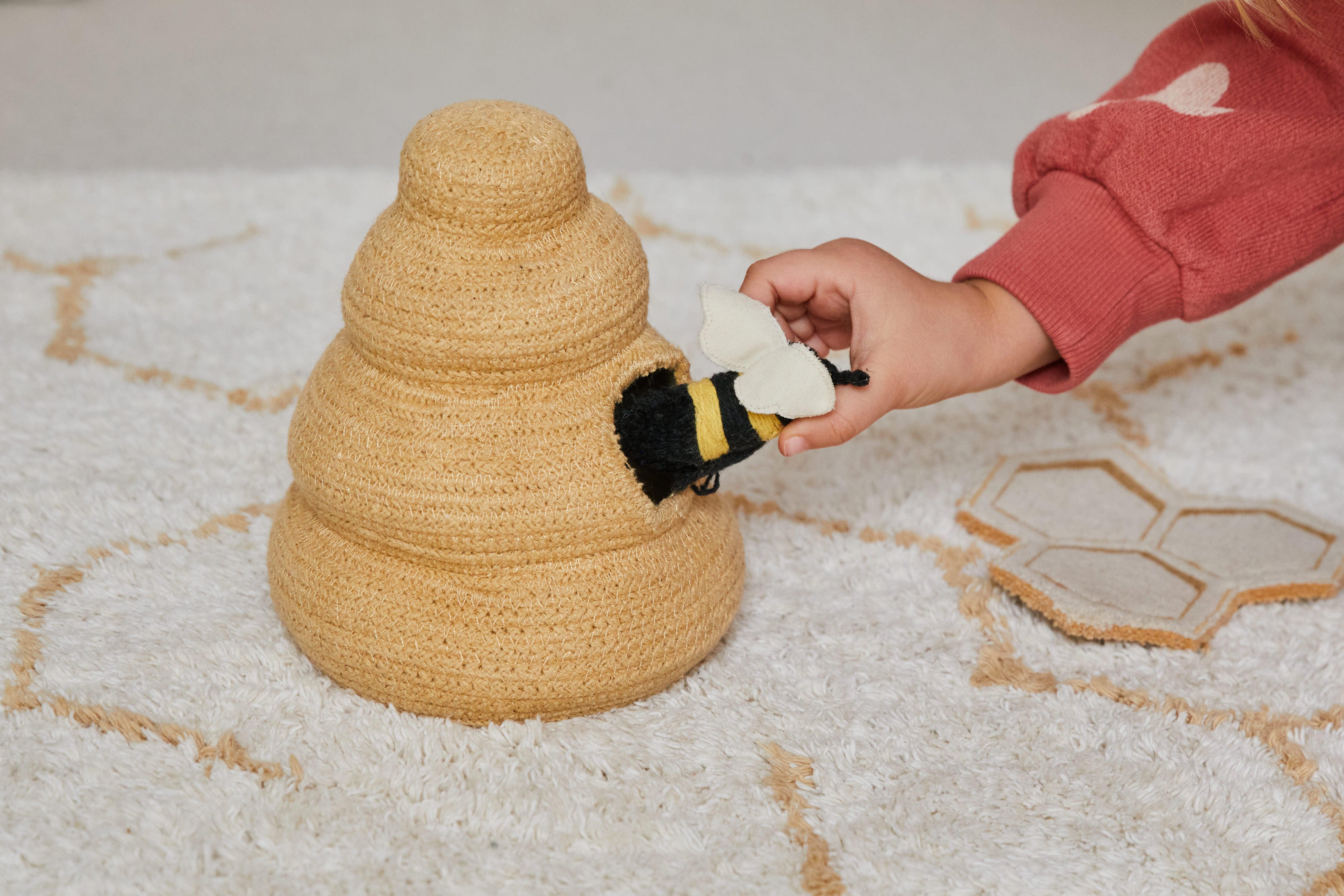 Cream rug with minimal yellow honeycomb pattern and honeybee toys