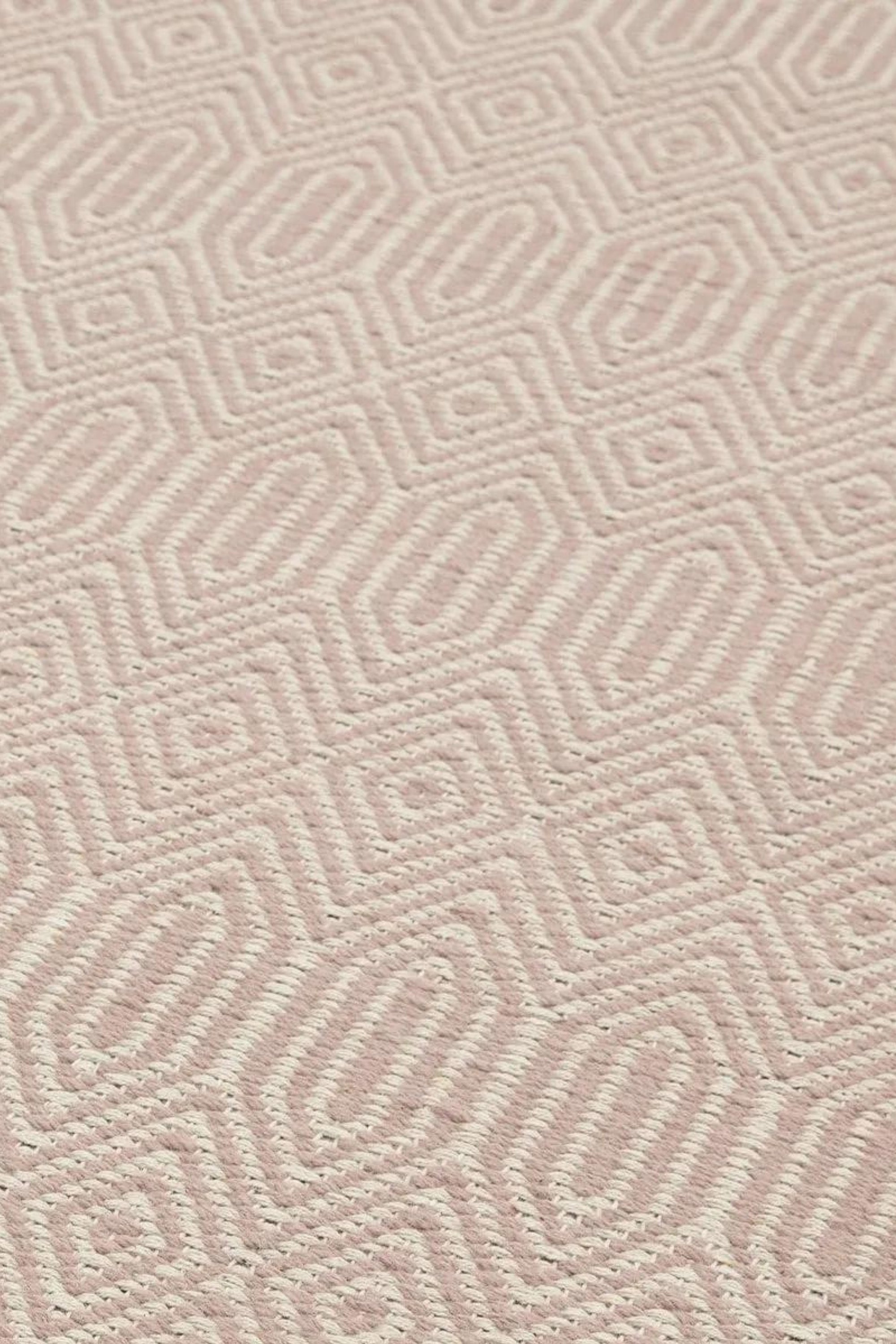 pink and white rug with a geometric aztec pattern