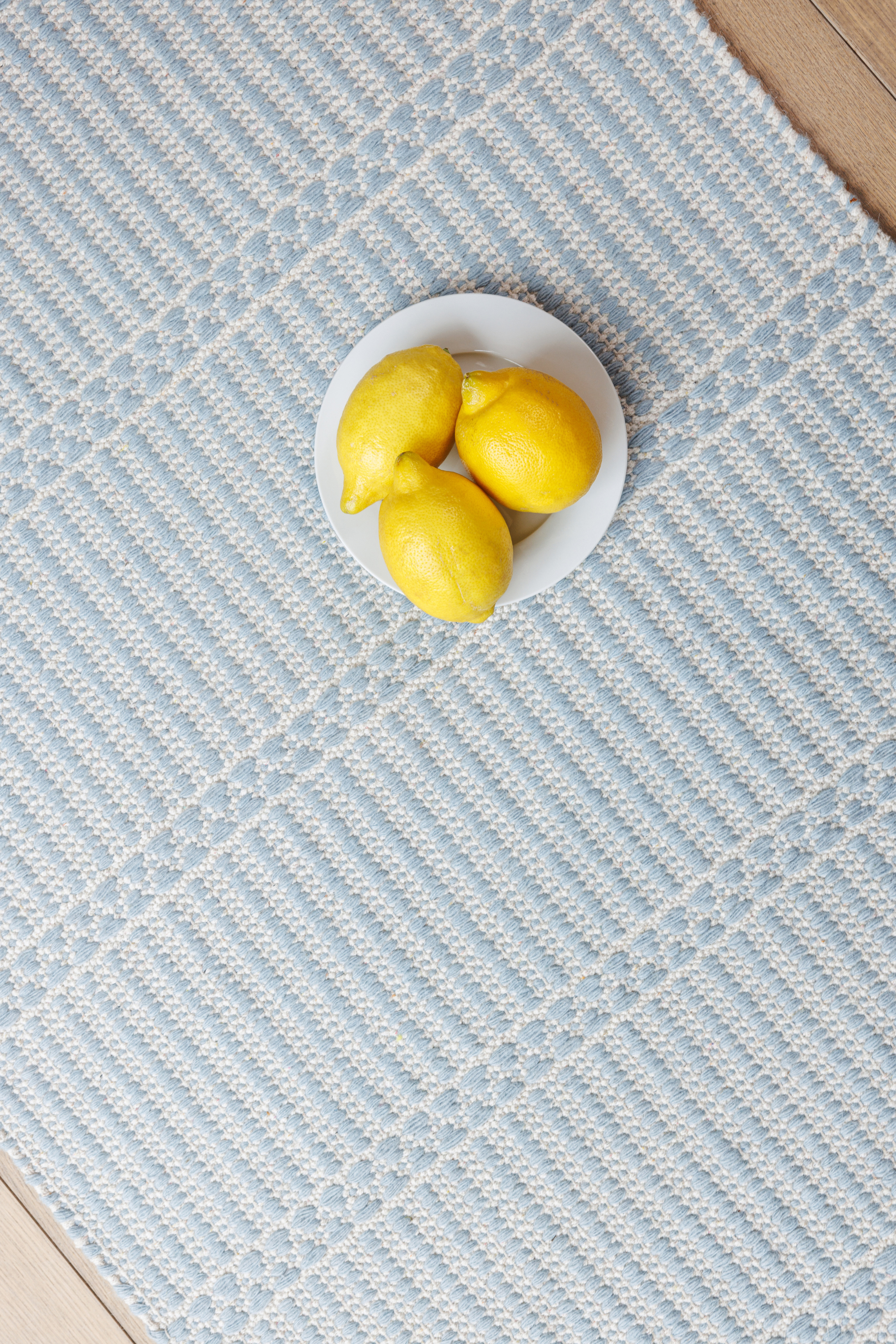 a plate of lemons on a blue wool and cotton runner rug featuring a design inspired by ancient irish script