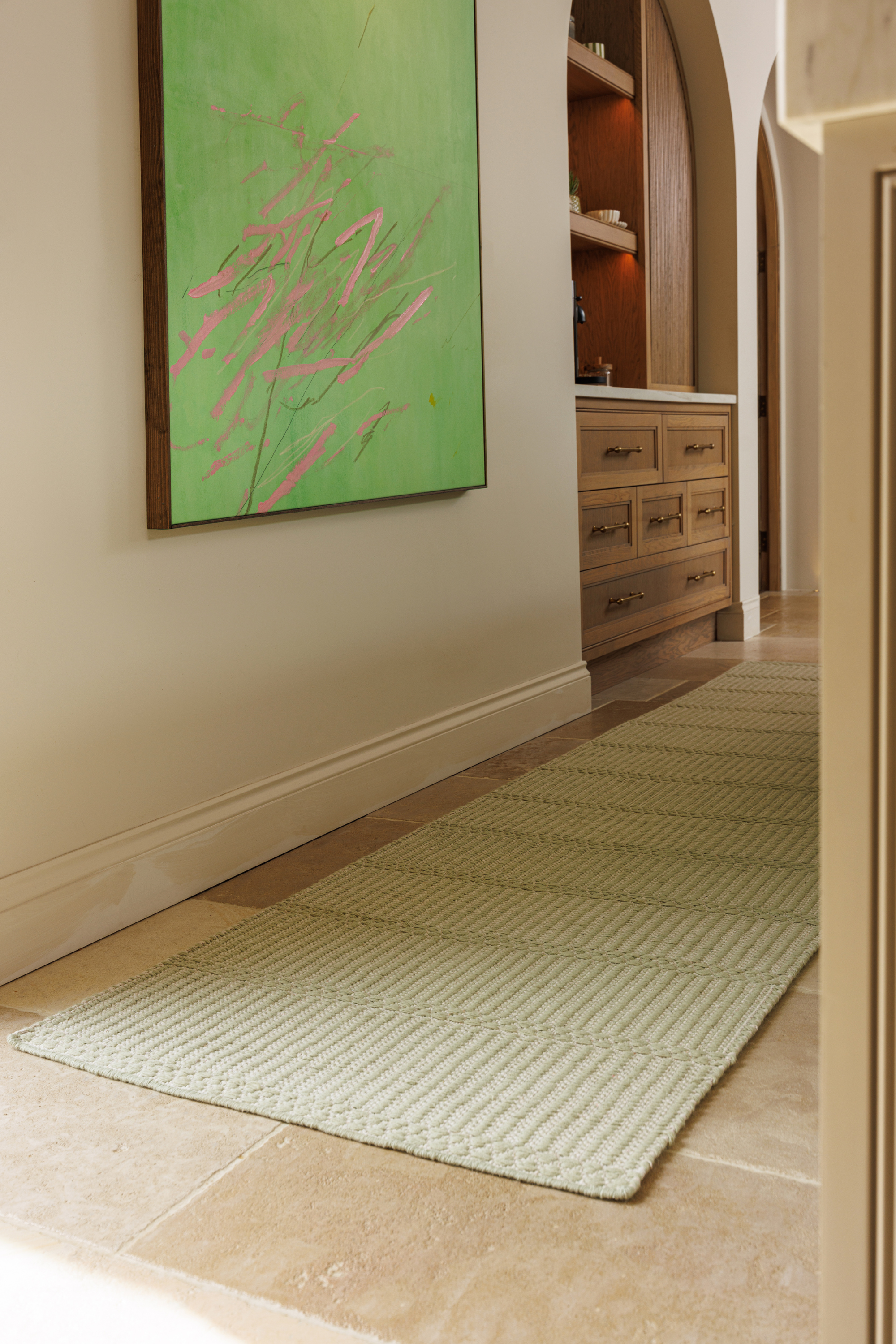 a wool and cotton runner rug in soft olive hues featuring a design inspired by ancient irish script placed in a kitchen