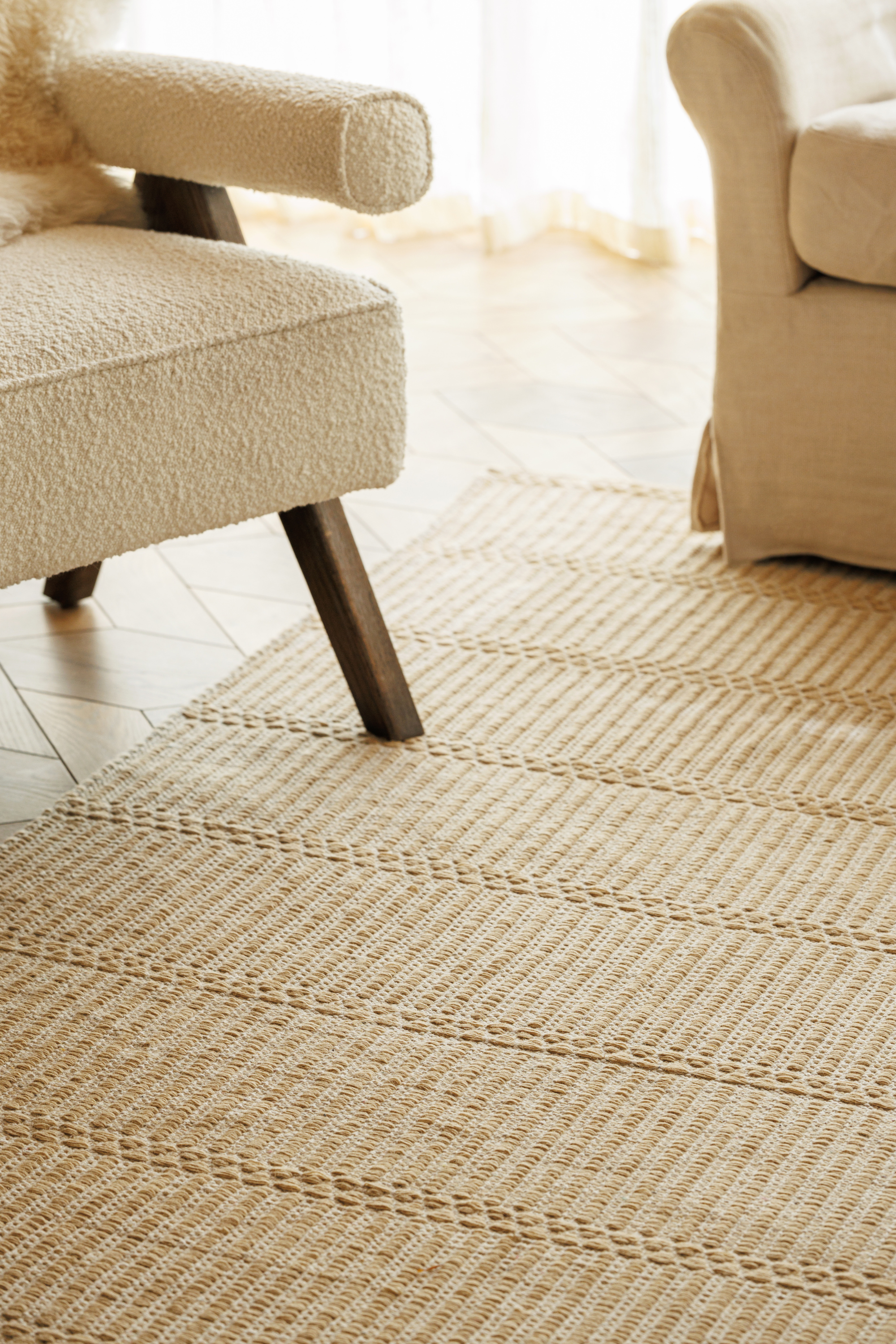 wool and cotton rug in a golden straw tone featuring a design inspired by ancient irish script placed under a couch in a living room