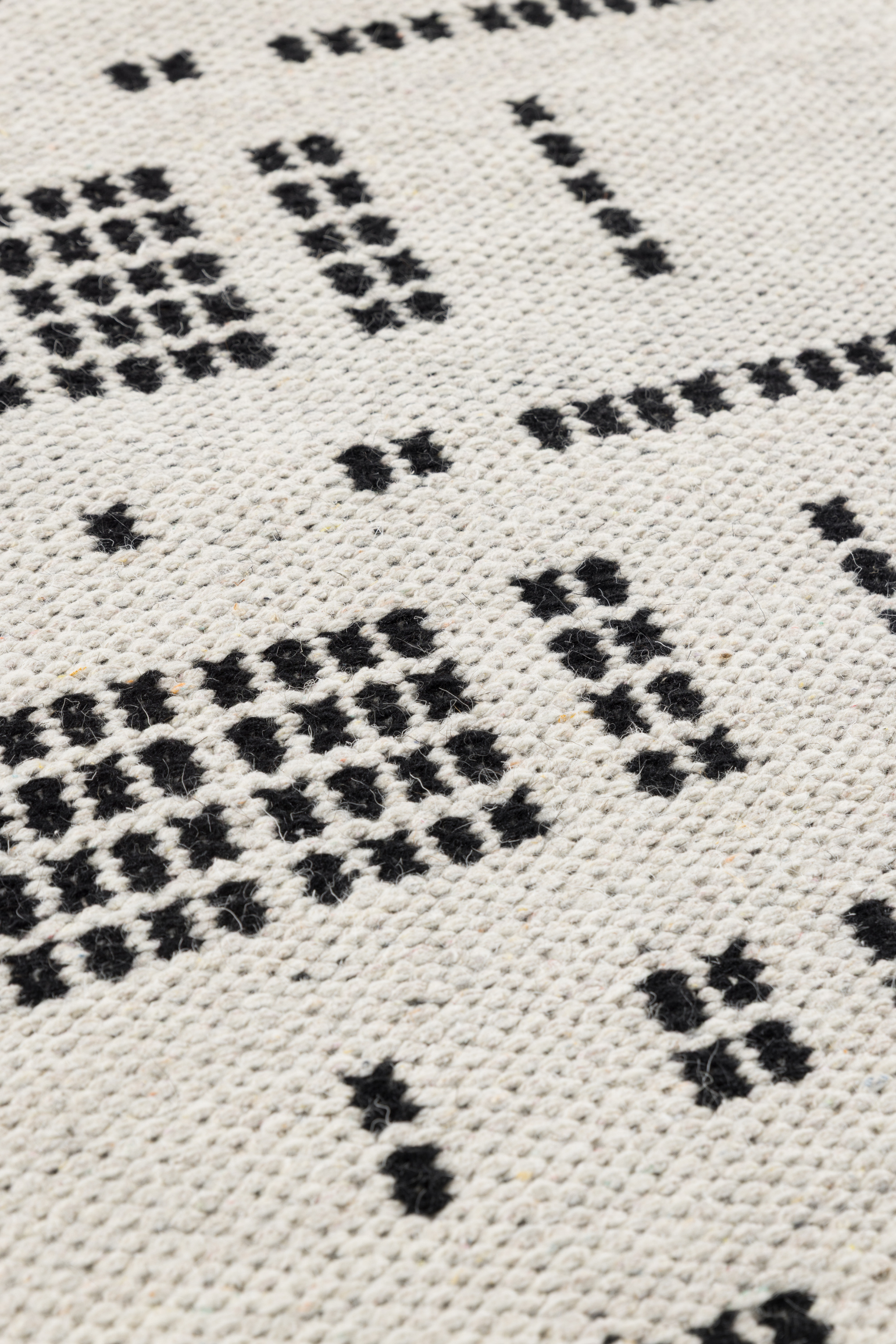 White wool and cotton rug with a black geometric pattern inspired by the Manhattan skyline at night