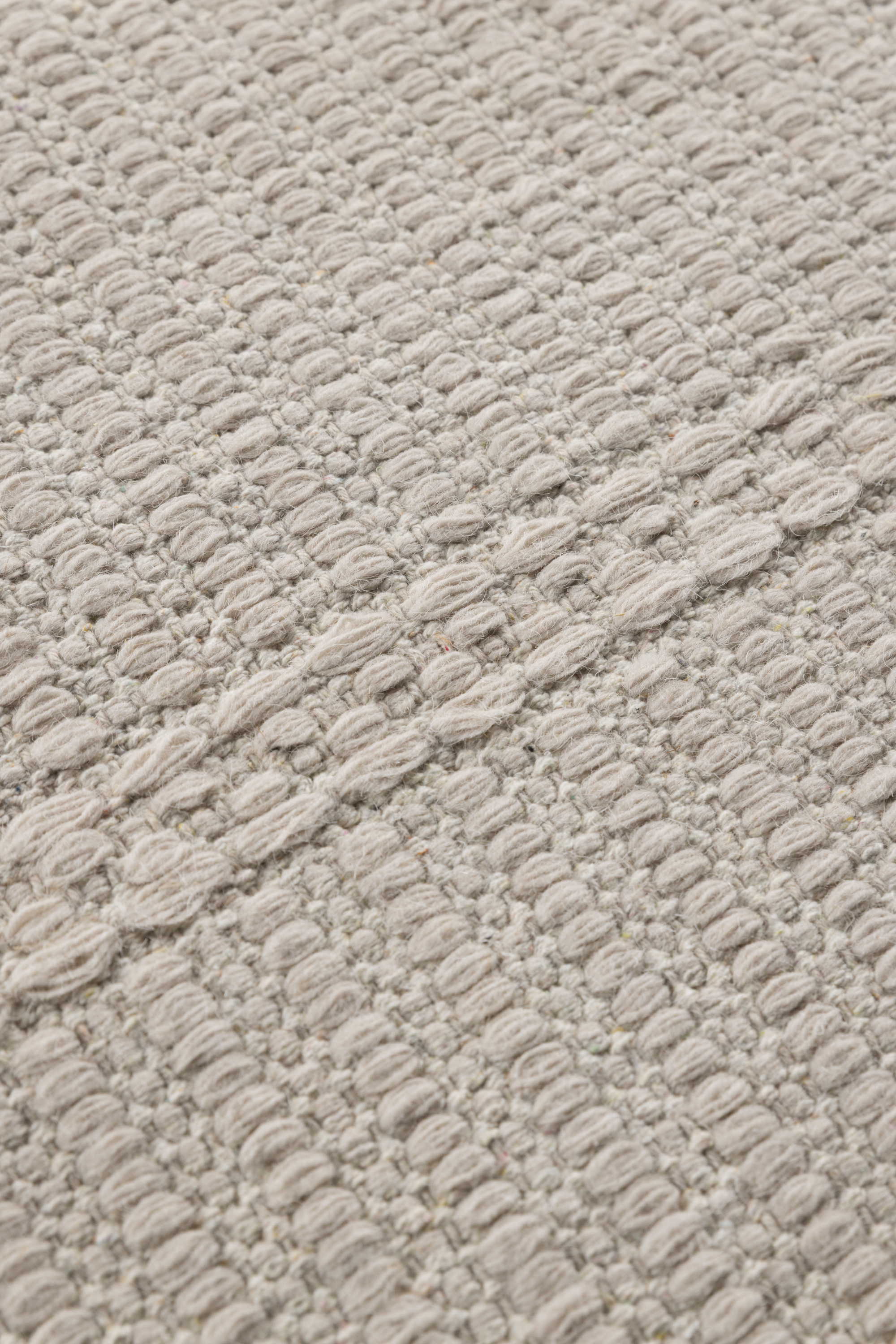 a close up of a beige wool and cotton runner rug featuring a design inspired by ancient irish script