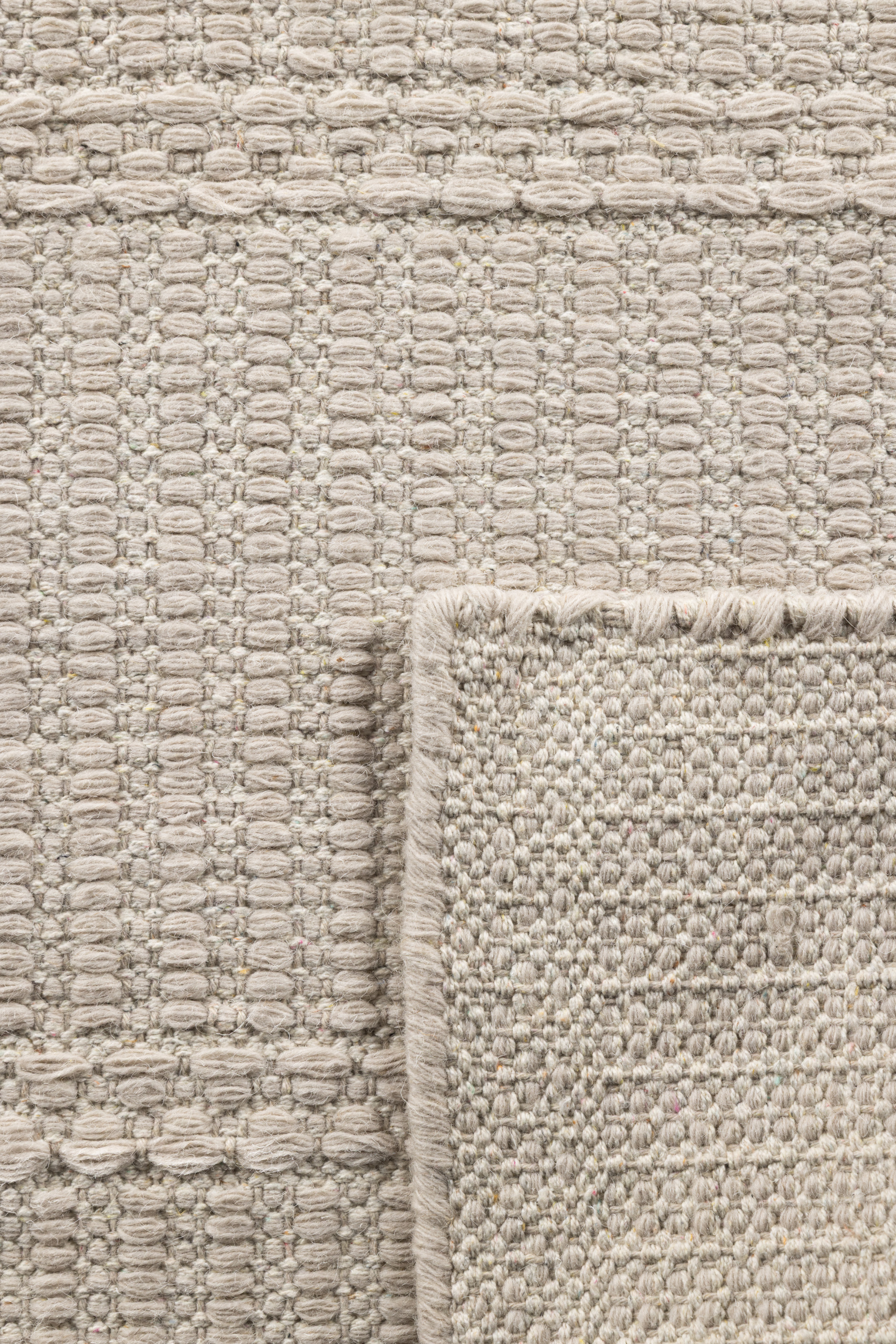 a close up of a beige wool and cotton runner rug featuring a design inspired by ancient irish script