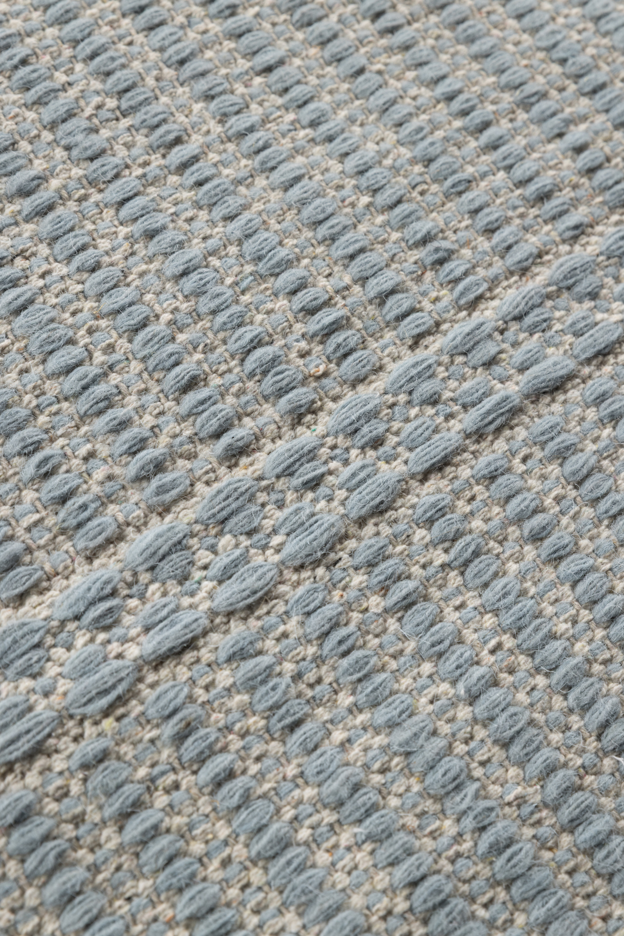 a close up of the pile on a blue wool and cotton runner rug featuring a design inspired by ancient irish script