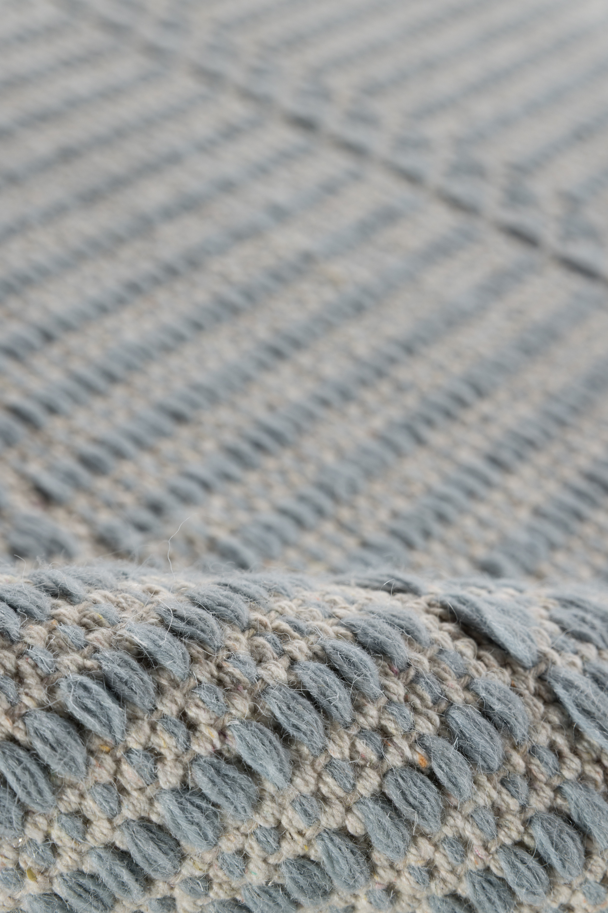 a closeup of a blue wool and cotton runner rug featuring a design inspired by ancient irish script