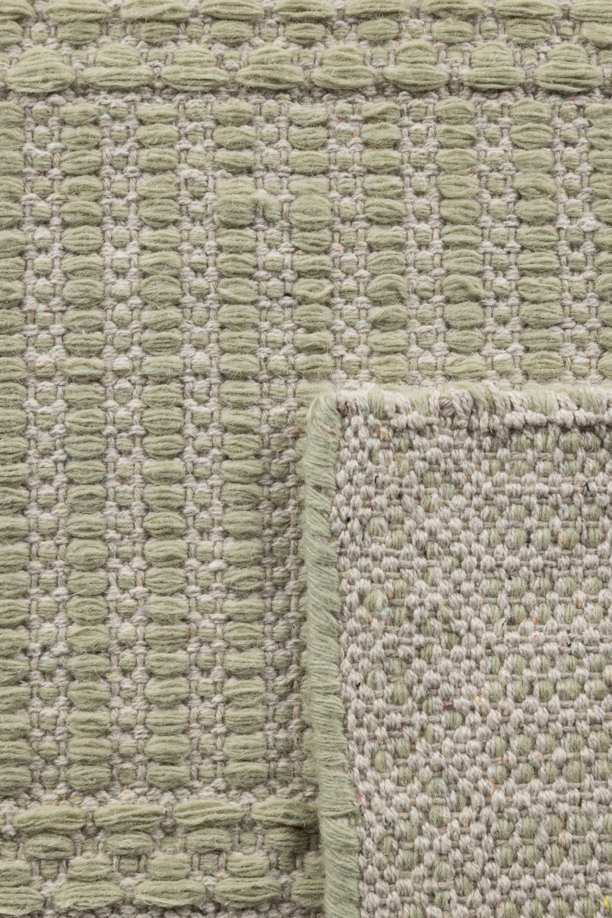 wool and cotton runner rug in soft olive hues featuring a design inspired by ancient irish script