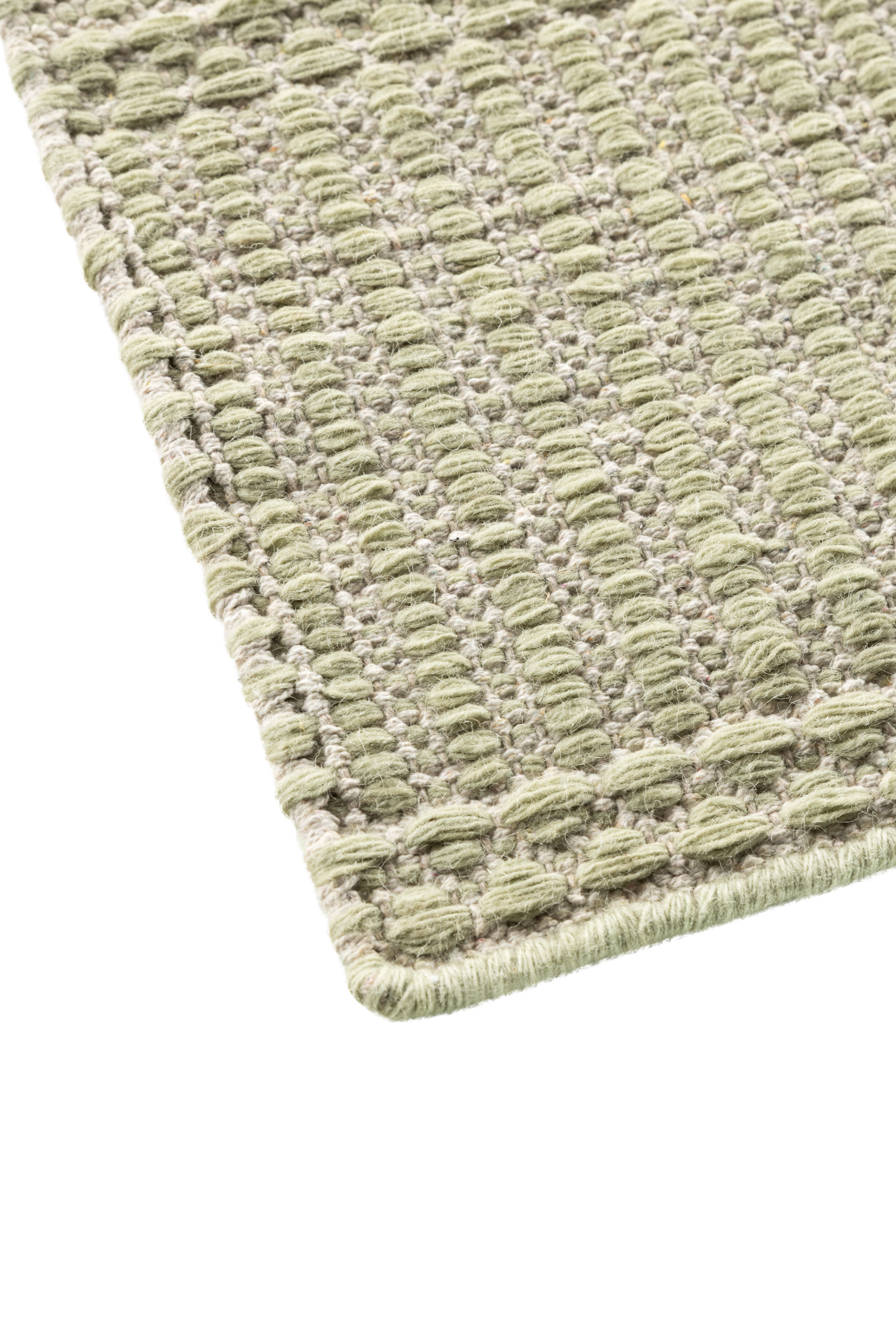 a close up of a wool and cotton runner rug in soft olive hues featuring a design inspired by ancient irish script