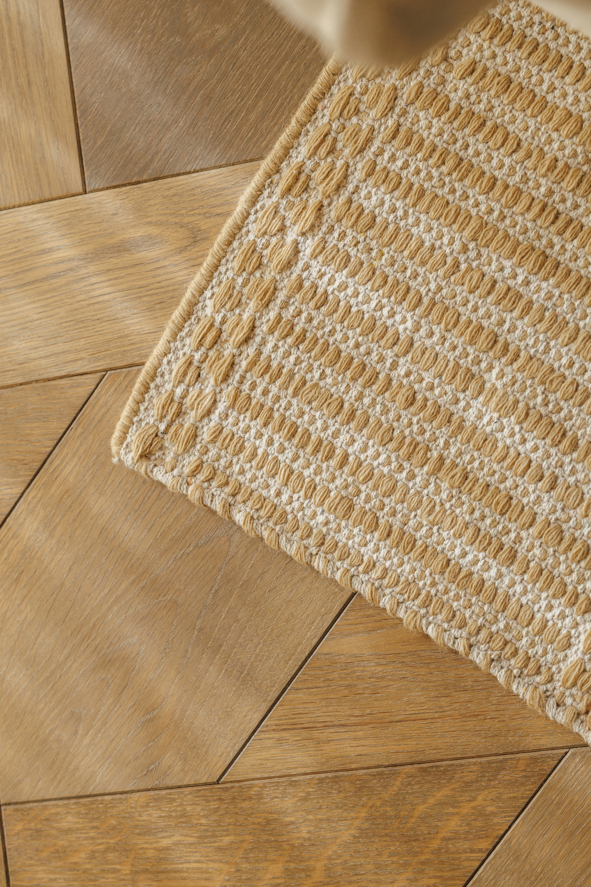 wool and cotton runner rug in a golden straw tone featuring a design inspired by ancient irish script