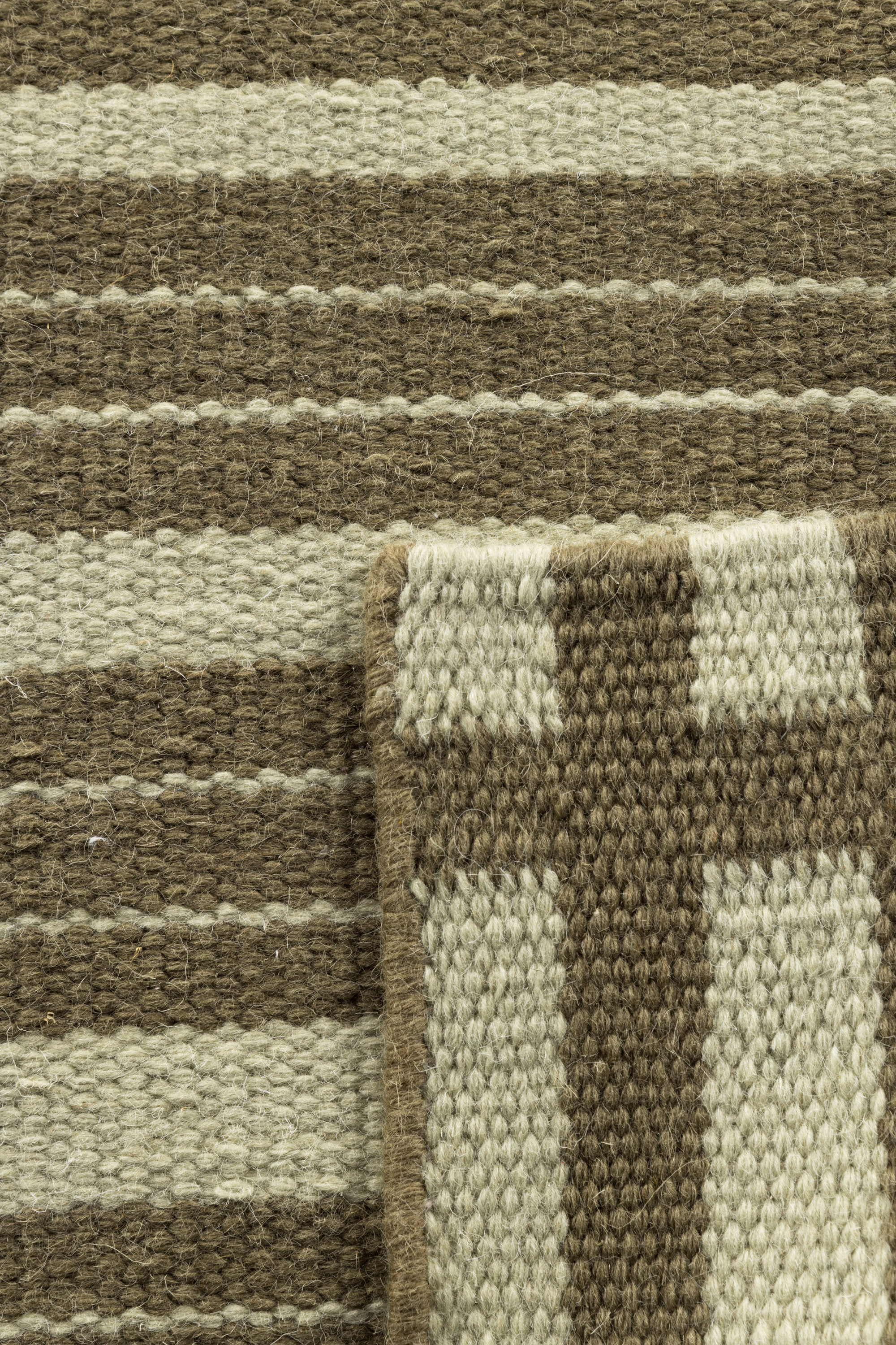 a closeup of a tonal green wool and cotton runner rug featuring a contrasting linear pattern