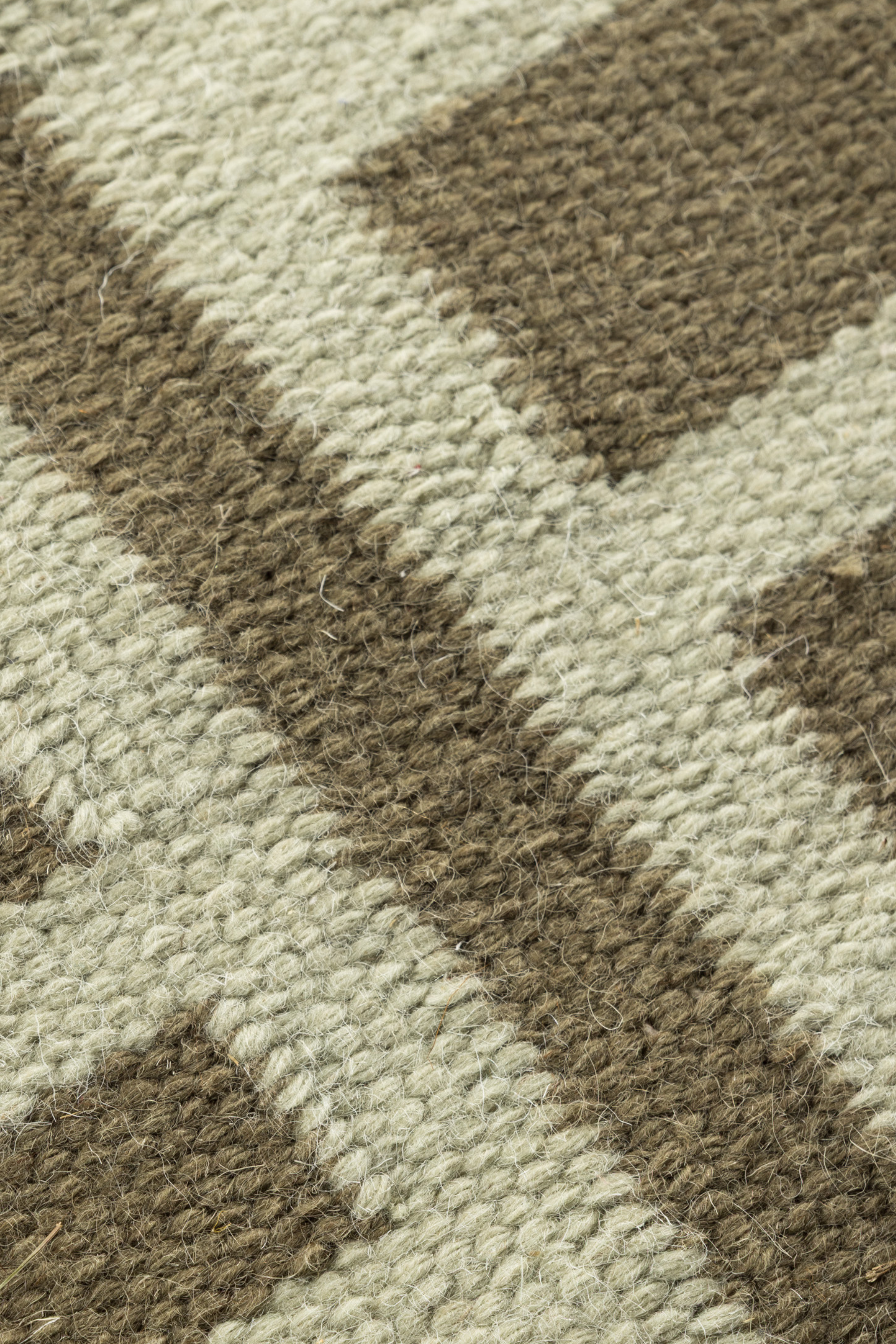 a close up of the pile on a tonal green wool and cotton rug featuring a contrasting linear pattern