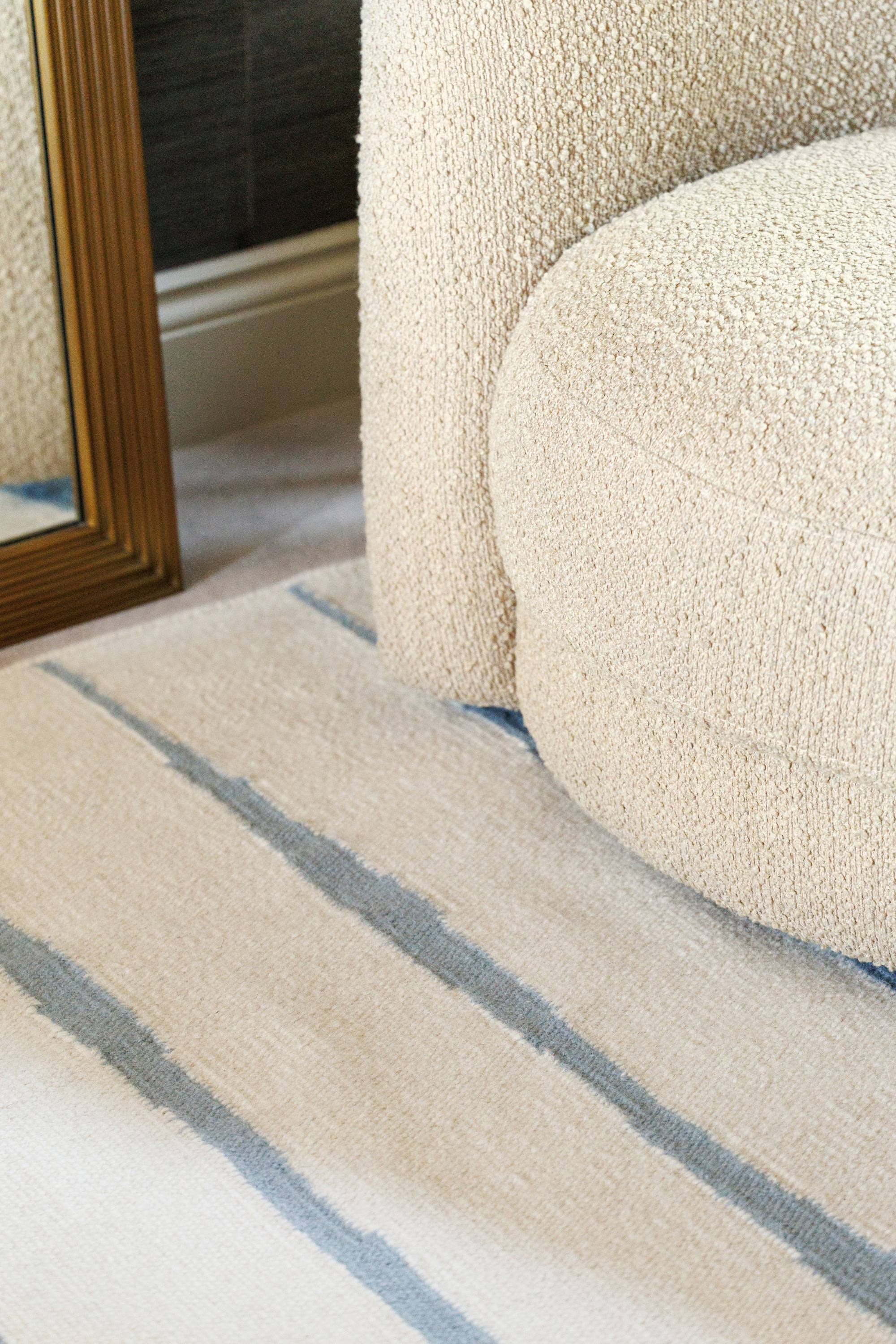 Neutral ivory wool and cotton flatweave rug featuring blue ripple linear lines
