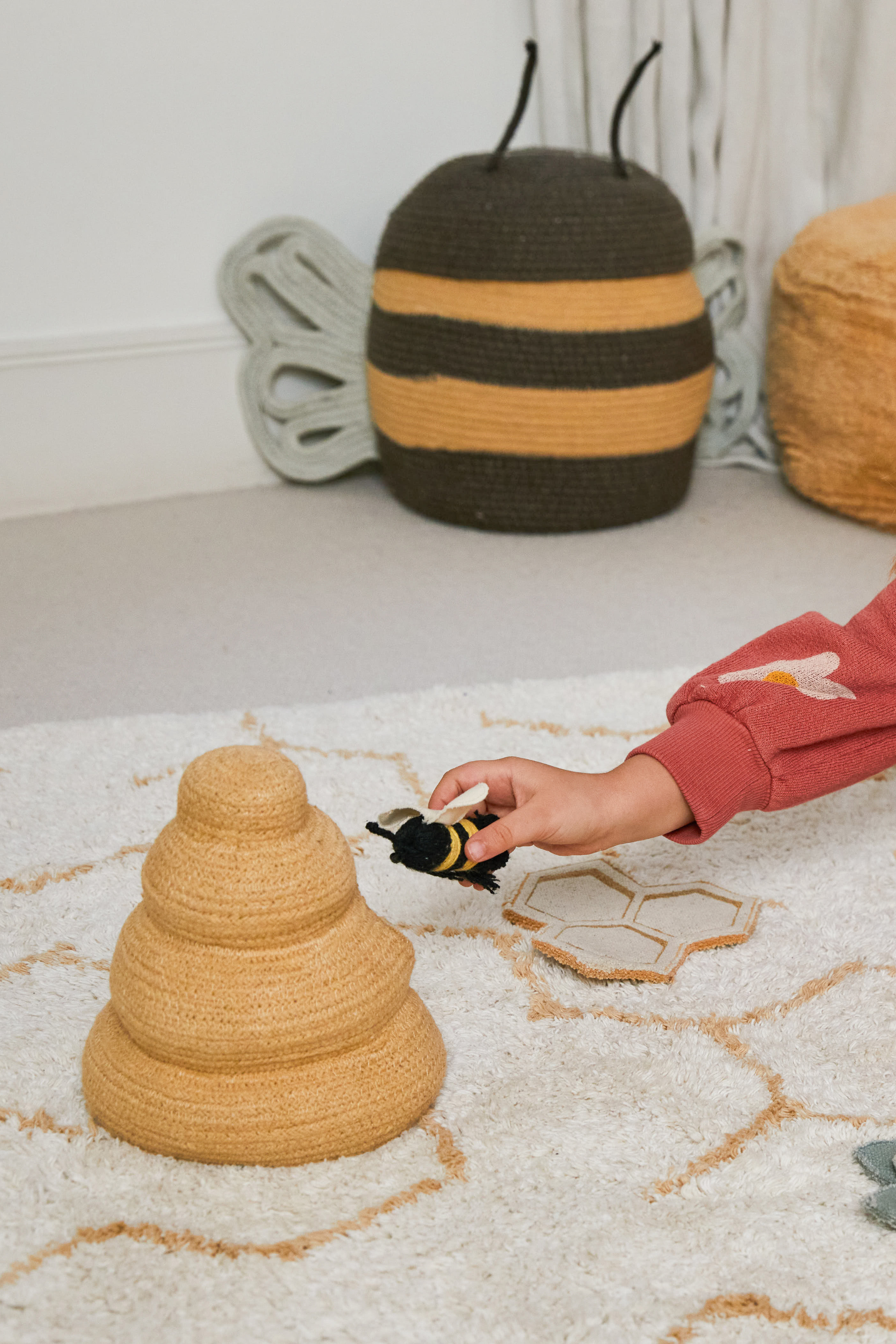 Cream rug with minimal yellow honeycomb pattern and honeybee toys