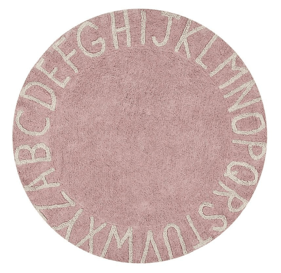 Circular pink cotton rug decorated with a natural beige alphabet border
