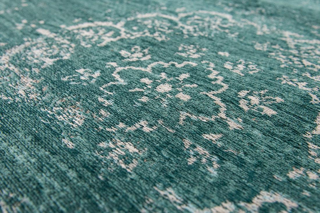 green flatweave rug with faded persian design