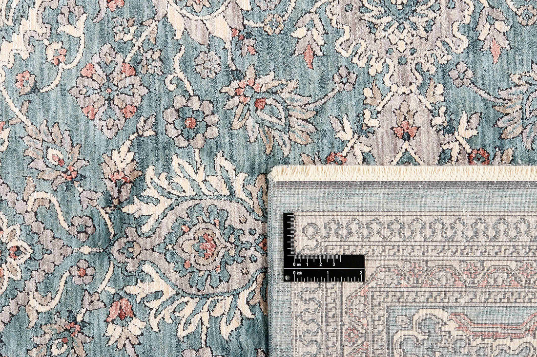 Traditional style rug with beige backing and teal patterned border design