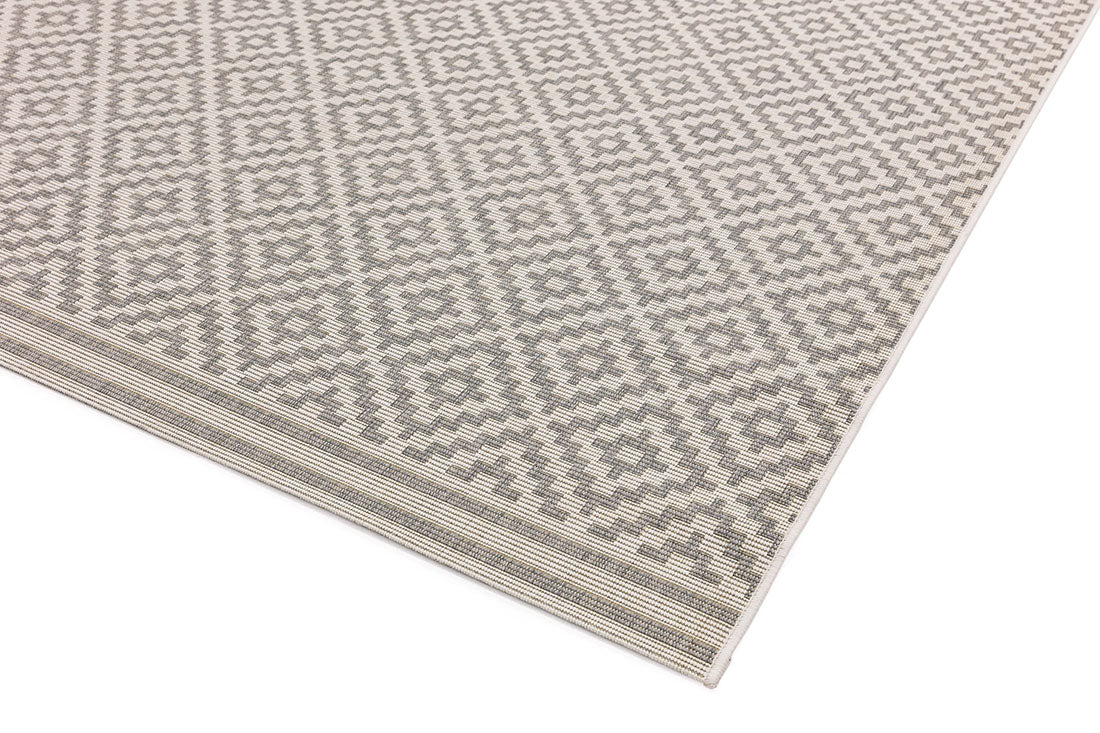 Woven grey and white rug with a modern geometric diamond pattern
