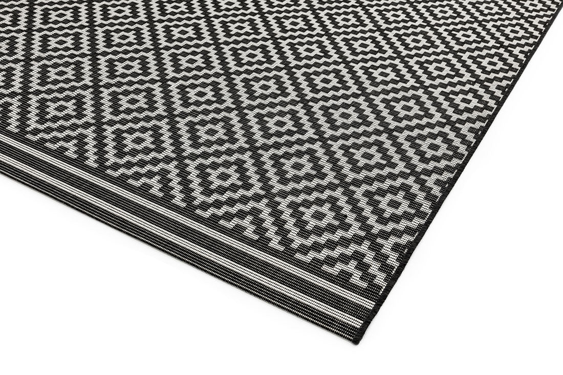 Woven grey and white rug with a modern geometric diamond pattern